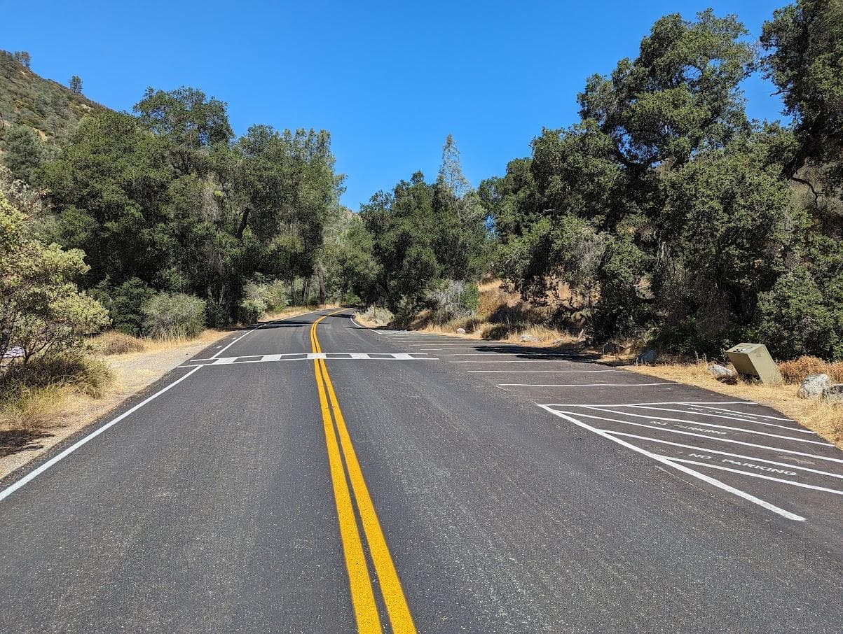 Newly paved road leading with small parking spaces located off the shoulder in dense vegetation