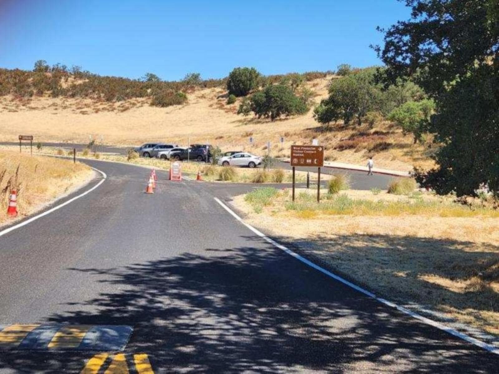 Road leading to a small paved parking area next to a hillside with sparse vegetation