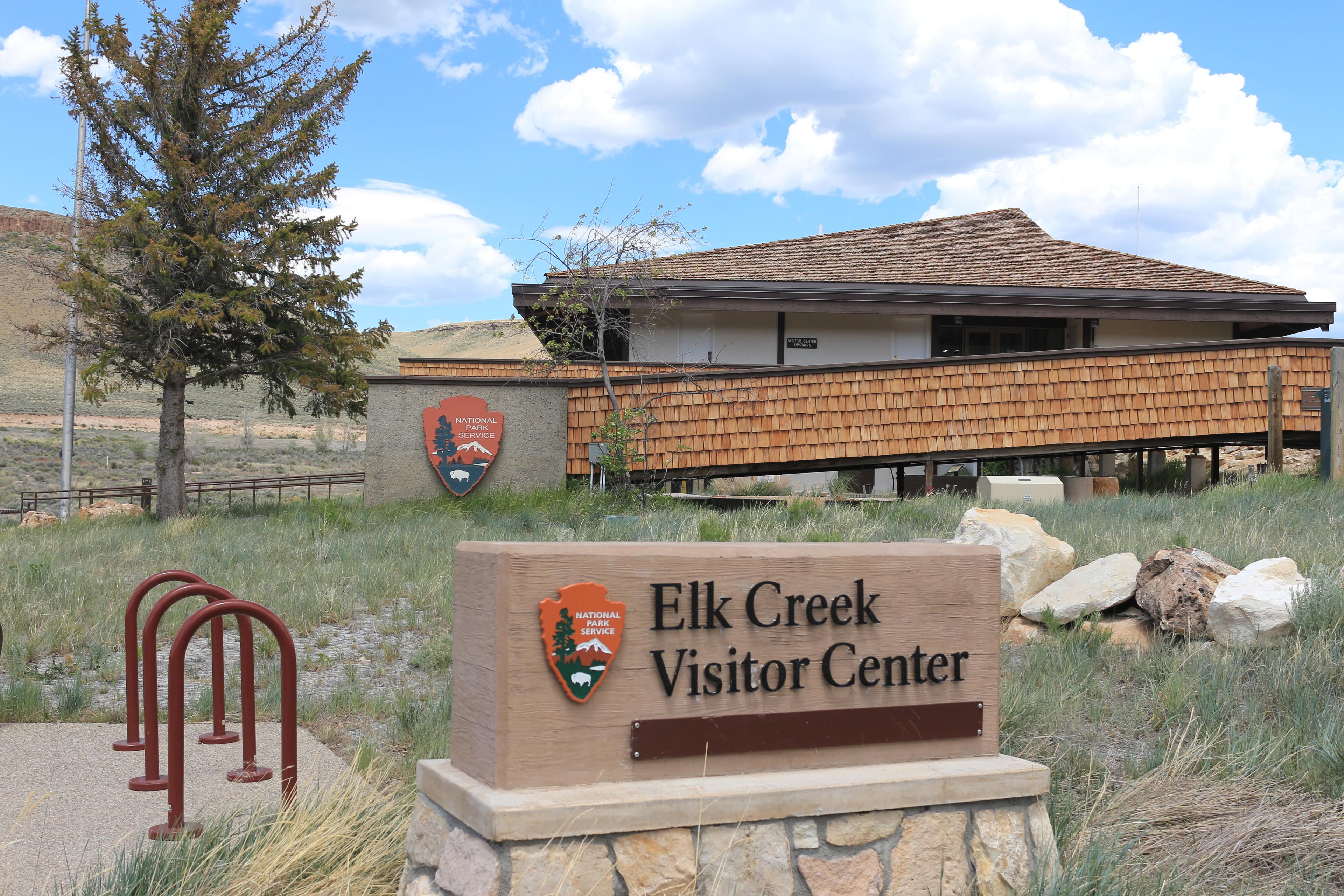 A brown and grey building with a concrete ramp and entrance sign with NPS arrowhead.