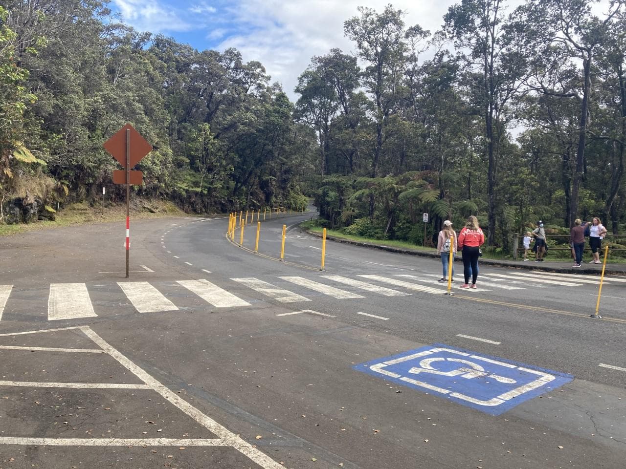 A group of people walk to the other side of a busy road on a crosswalk.