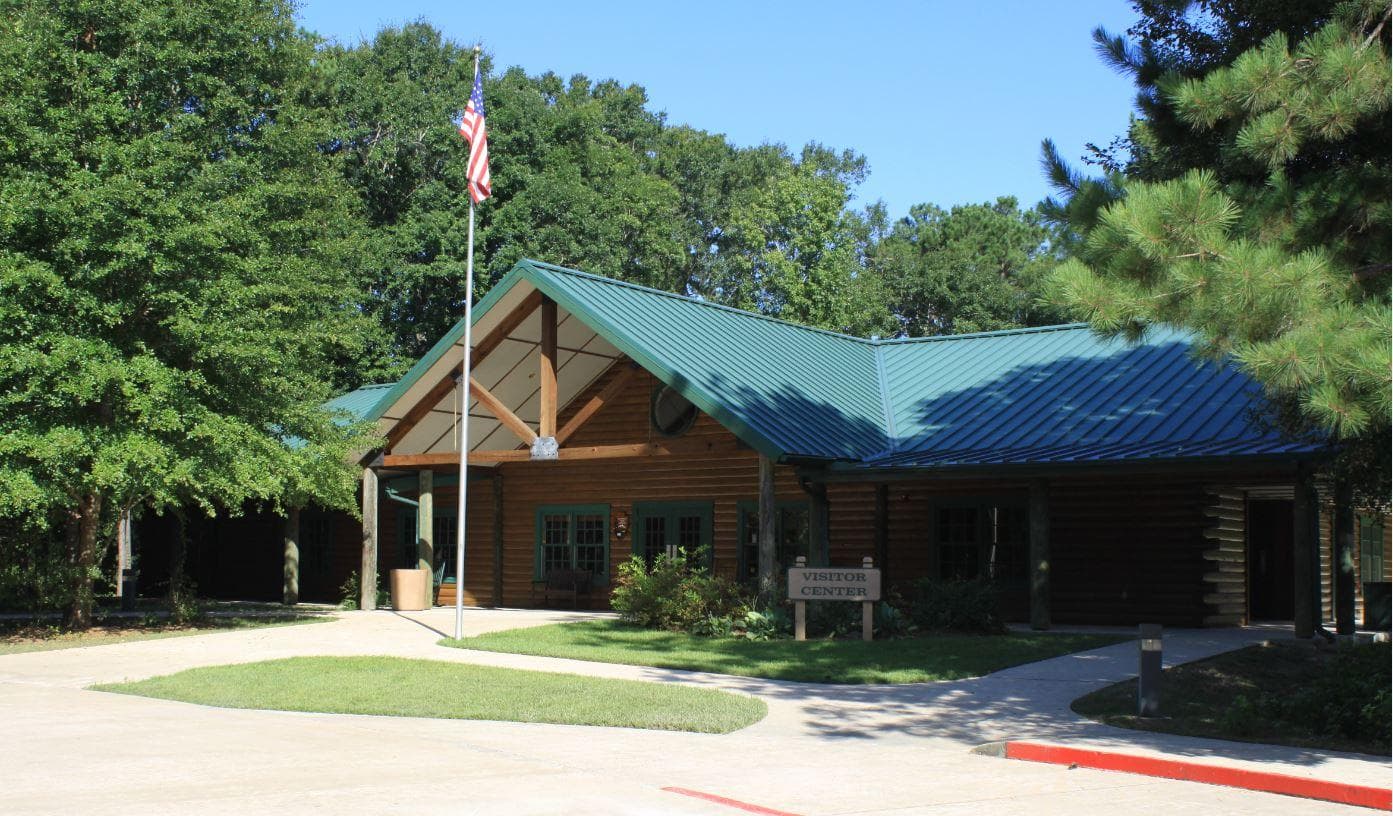 A log cabin style visitor center with a green roof surrounded by trees.