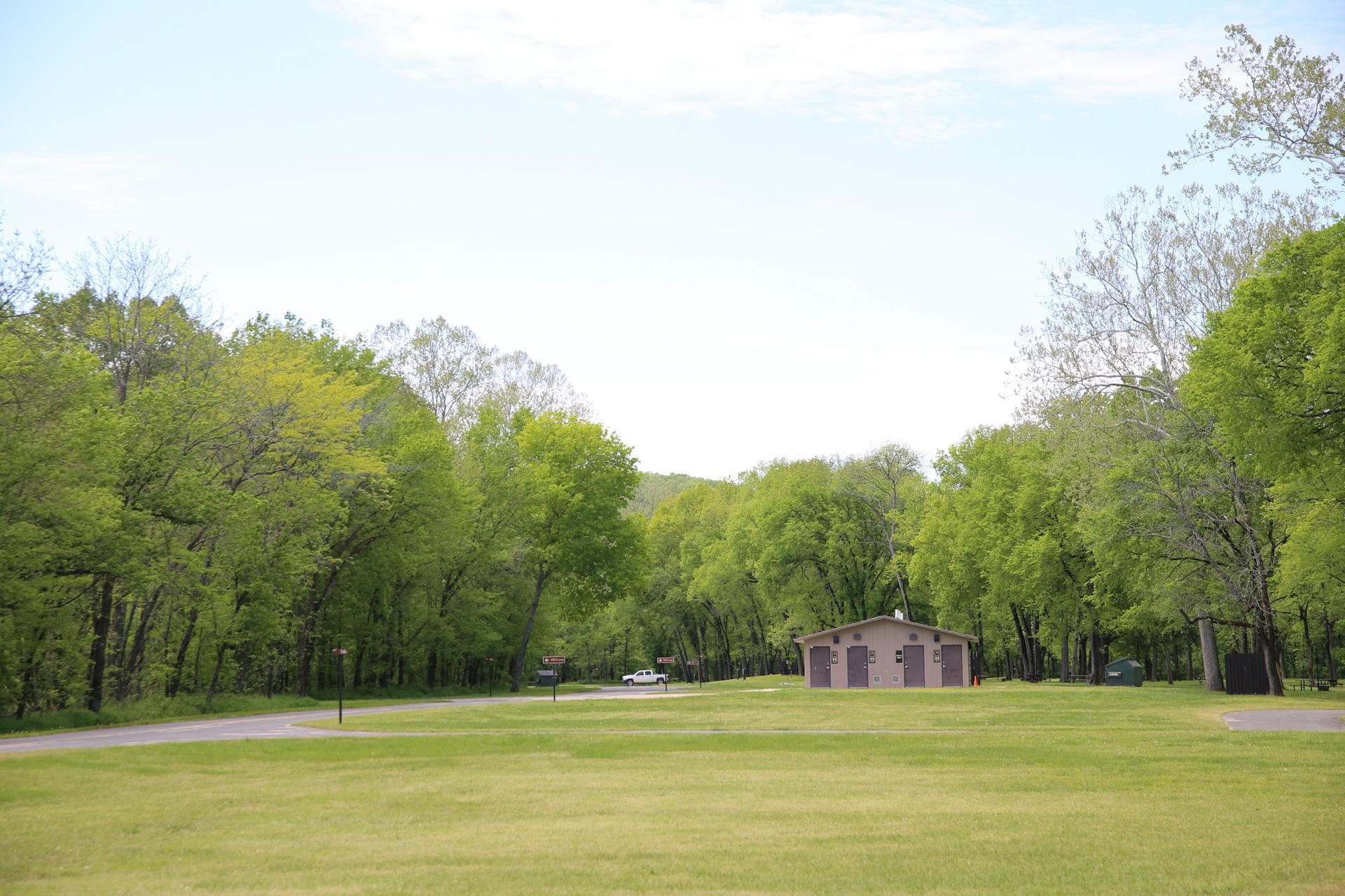 A large grassy field with a restroom at the end.