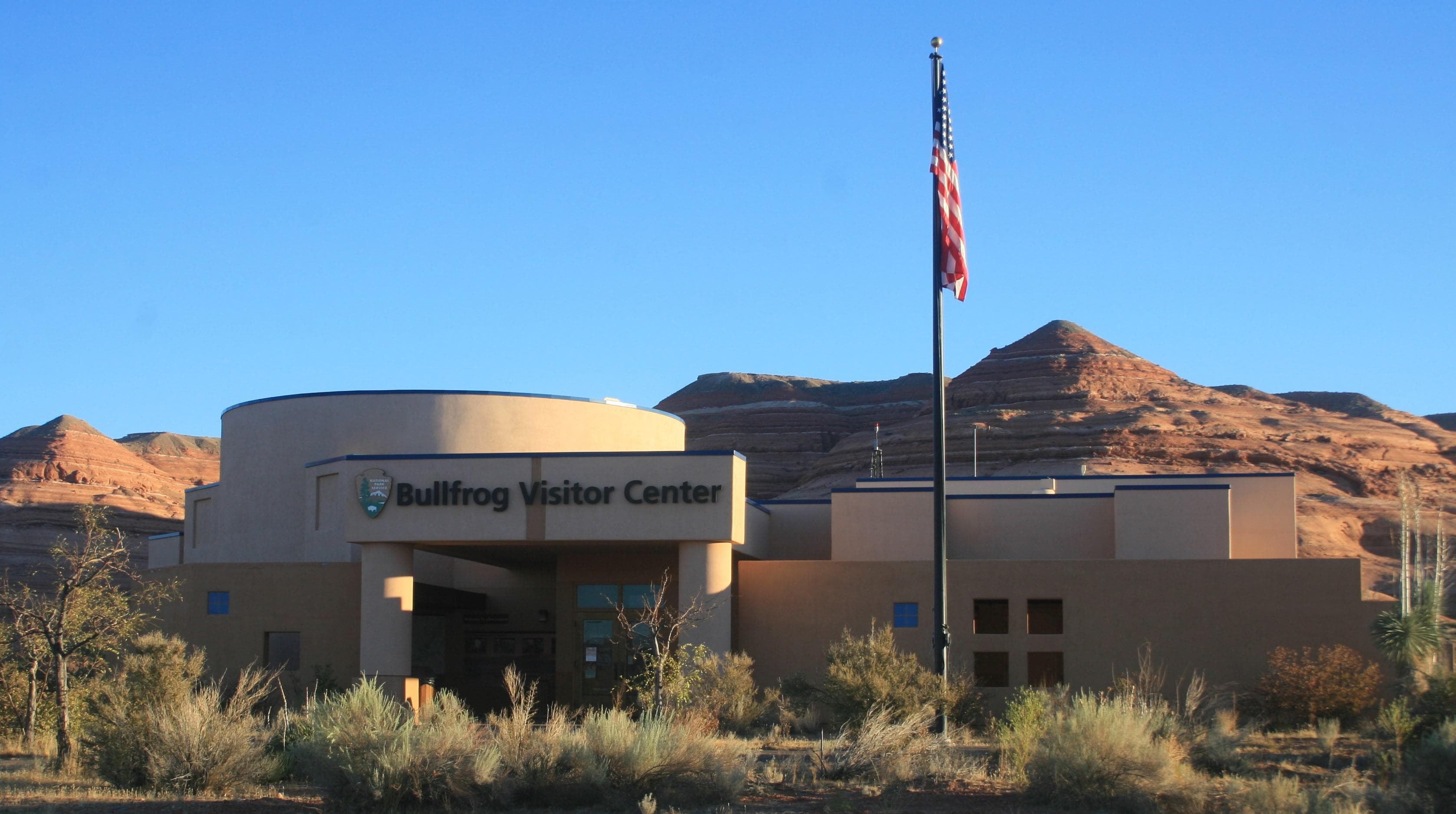 Modern building with sandstone cliffs in background. Bullfrog Visitor Center sin side of building.