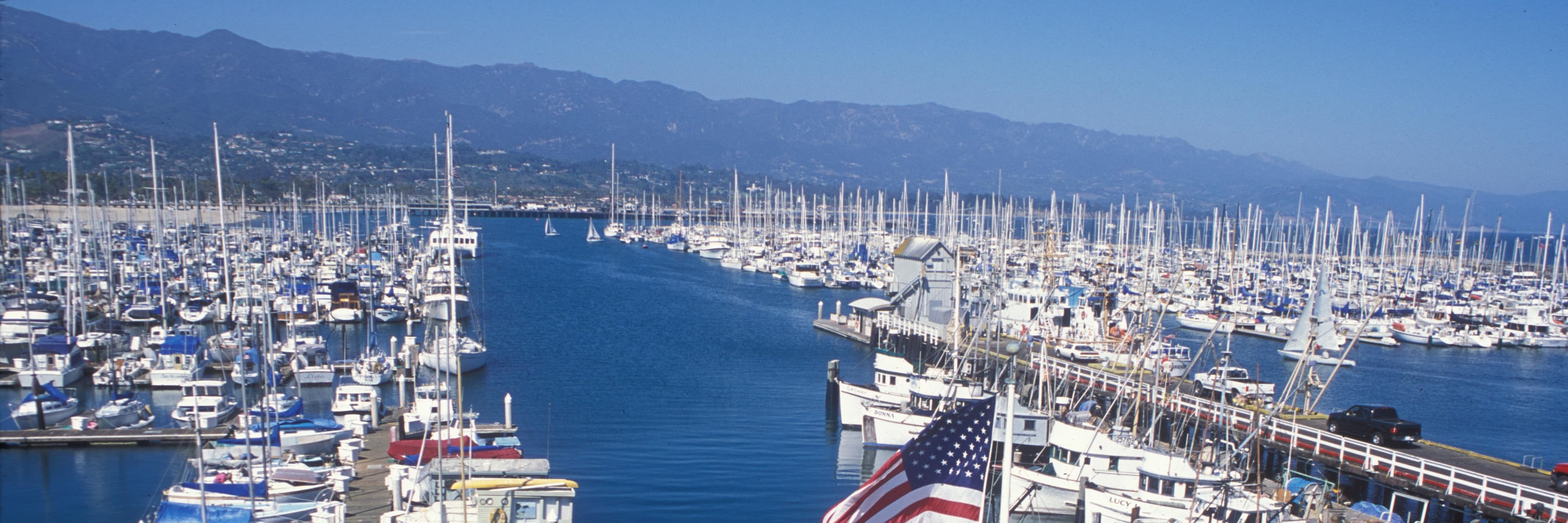 View of harbor with boats and tall mountains.