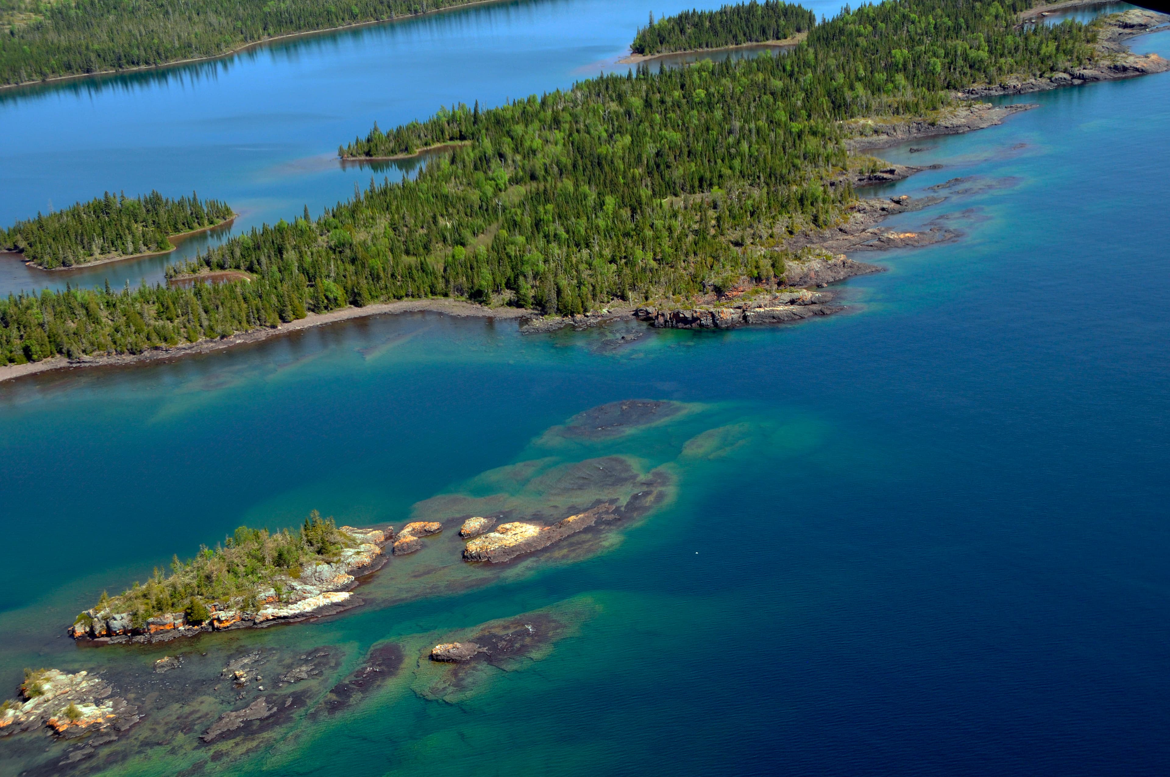 Aerial view of West Caribou Island surrounded by the blue waters of Lake Superior.