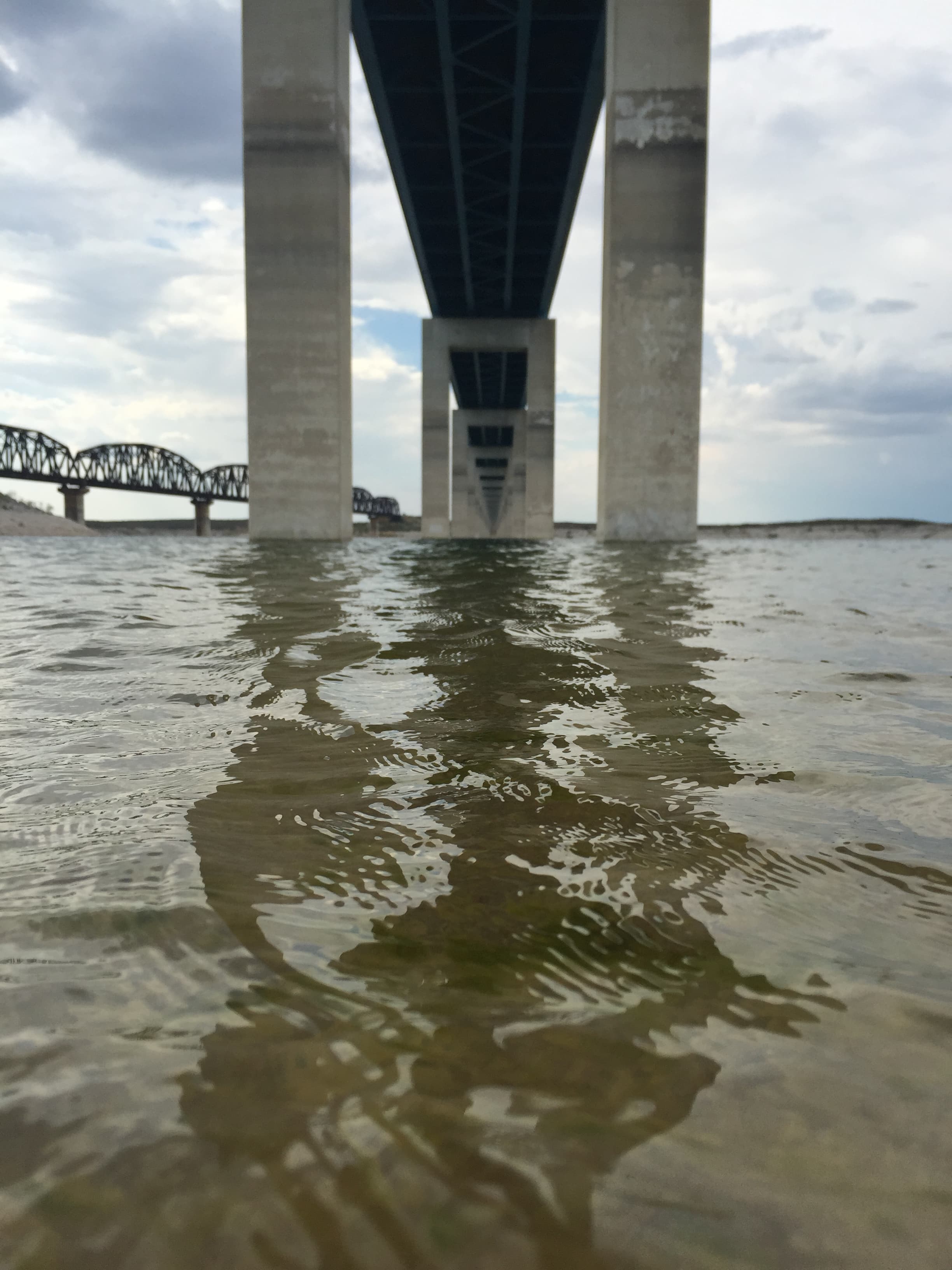 Taken from a boat on the water, the image shows the underbelly of a bridge and the supports.