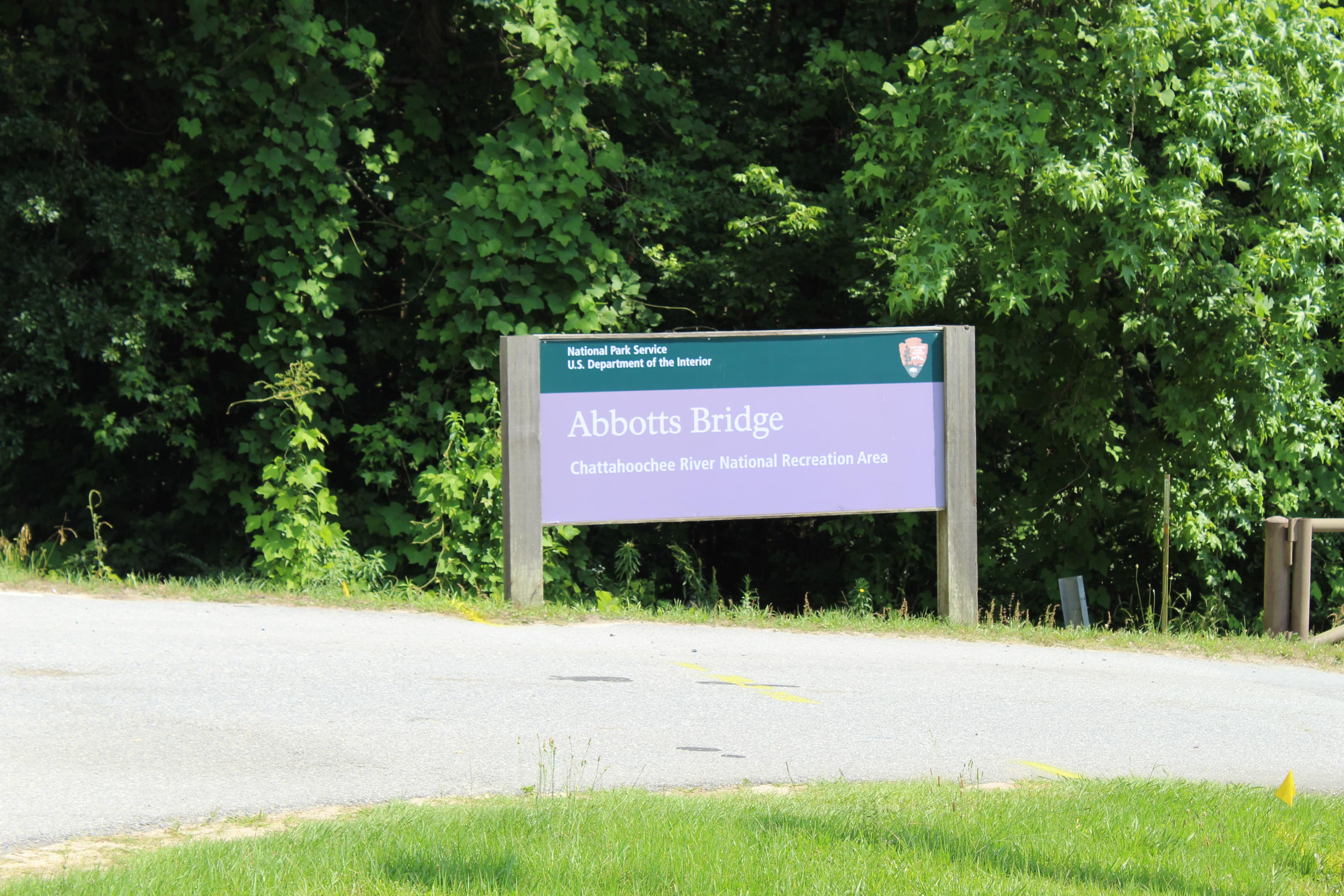 Entrance sign with the park and unit name behind road with trees in the background..