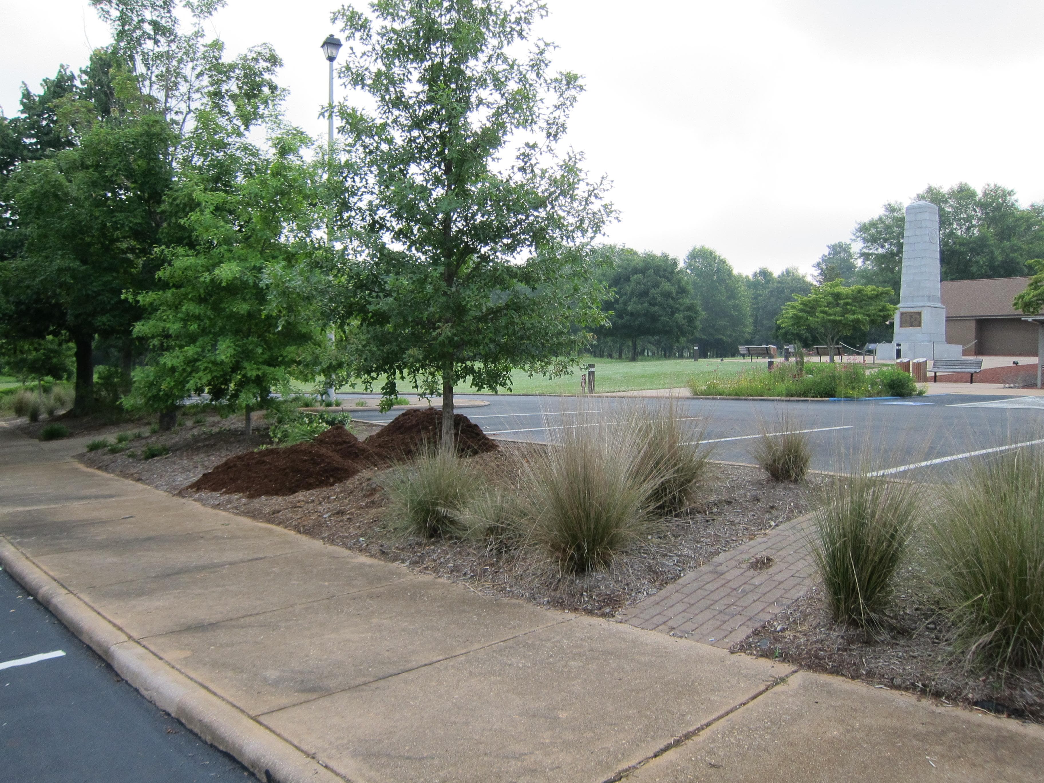Sidewalk, trees and low plants, parking spaces, US Monument, and Visitor Center
