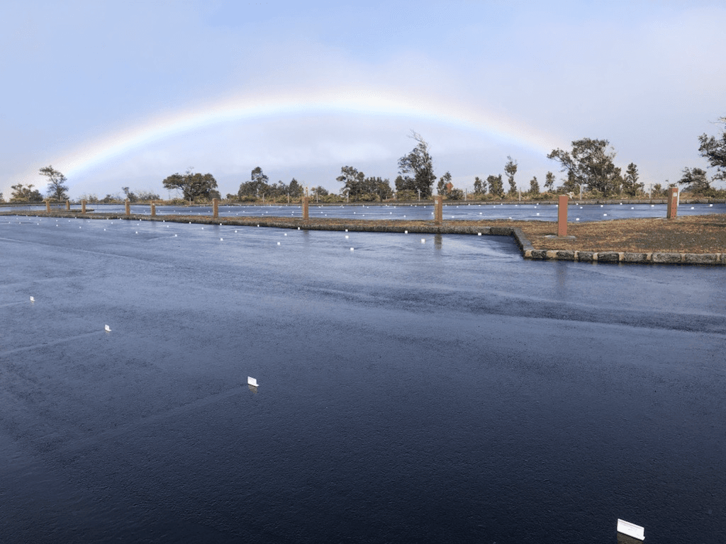 A vibrant rainbow appearing over an empty parking lot.