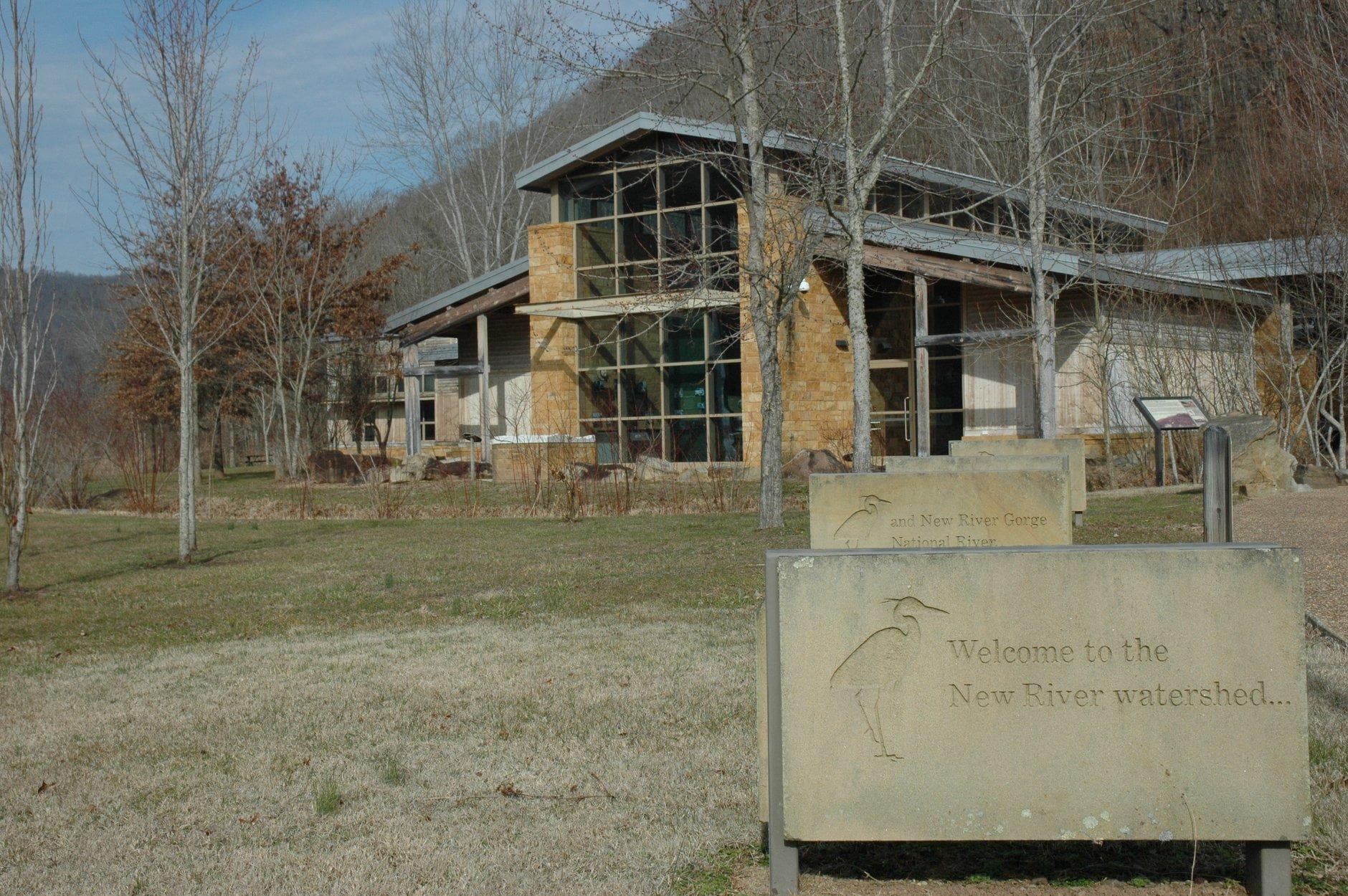 stone and glass building with grass and trees around it