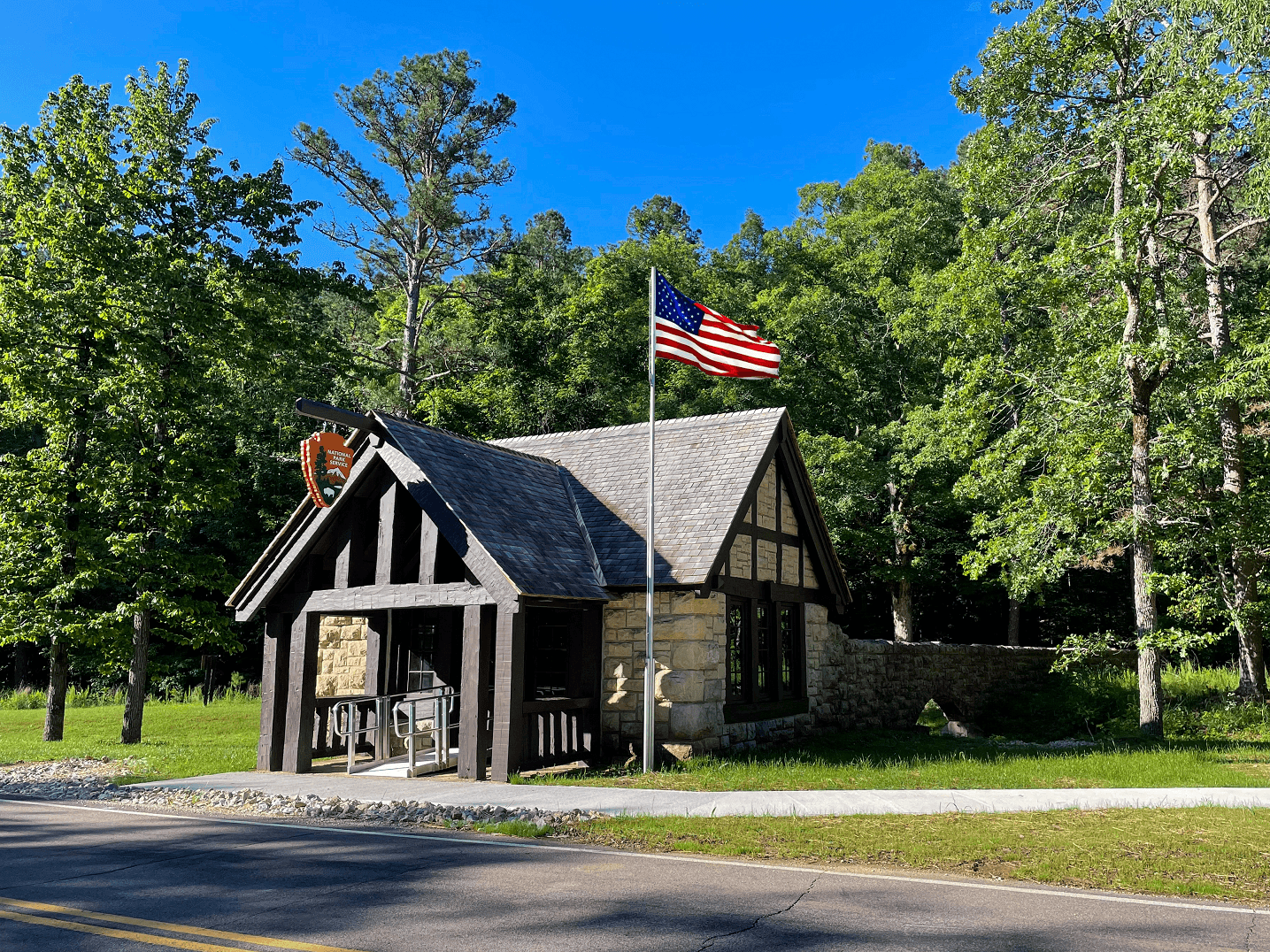 A rustic, CCC-era building with a US flag and NPS arrowhead.