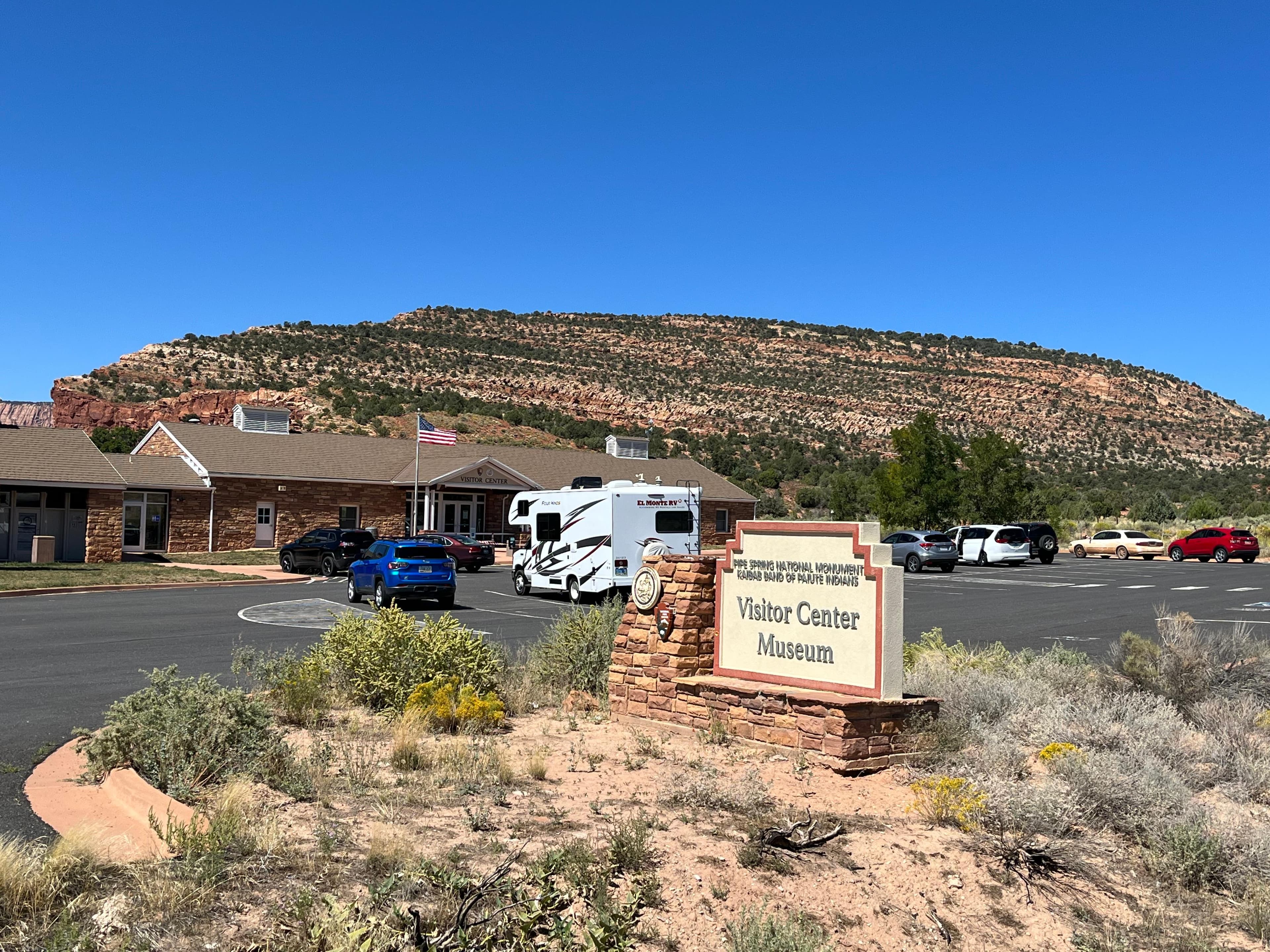 A large sign reads Visitor Center Museum, in the background is a parking lot and building.