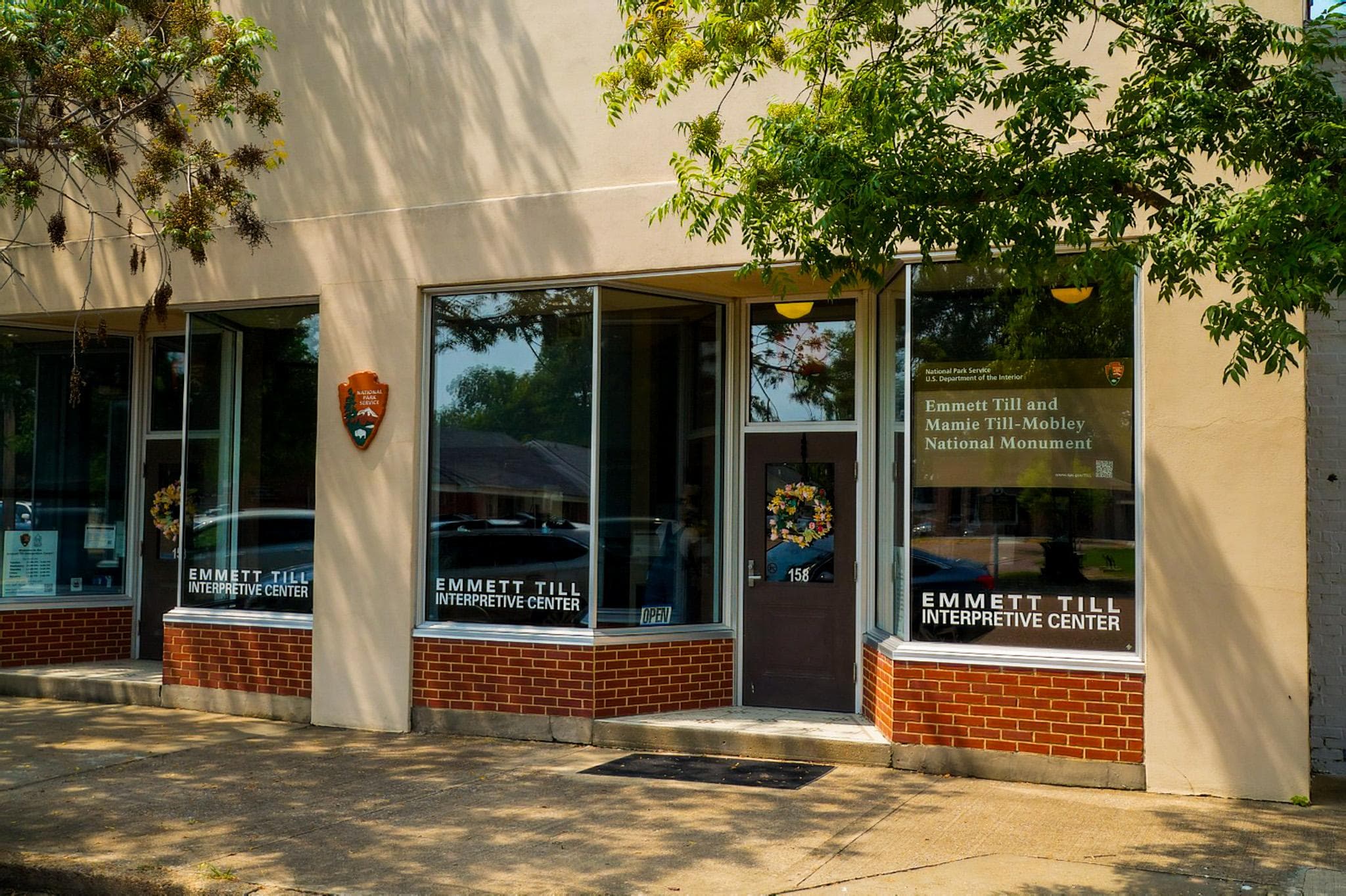 Exterior of a tan building resembling an old storefront. An NPS arrowhead hangs in the center.