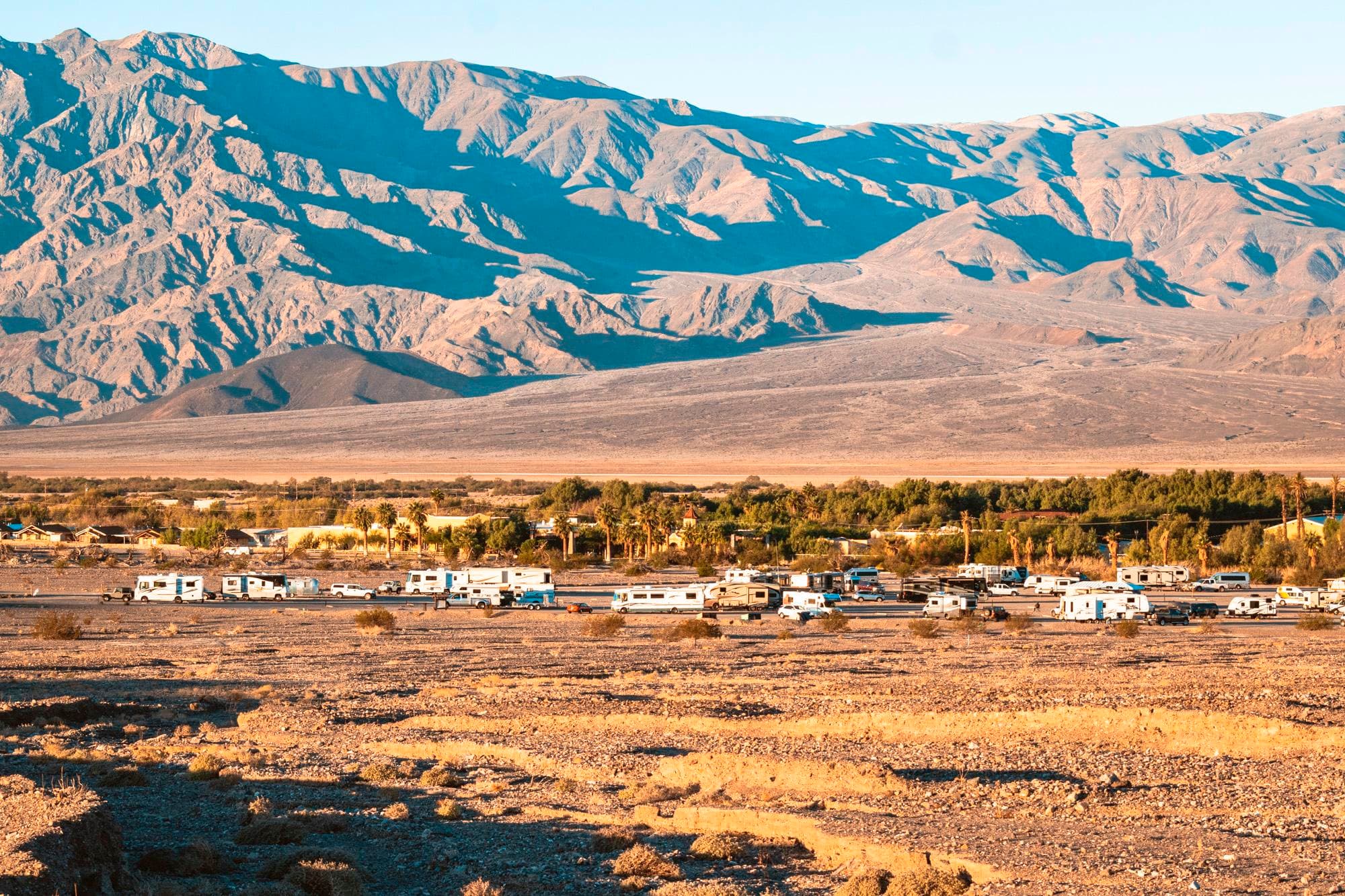 a long distance view of RVs and trailers in a gravel area with distant mountains