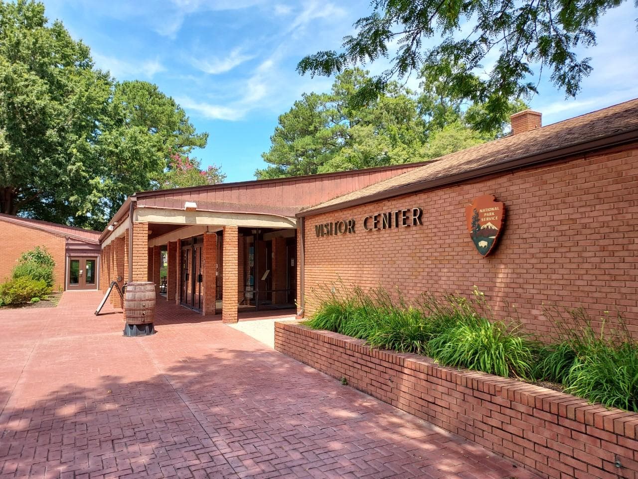 Brick one story building with entrance doors under porch. American flag flying in the front