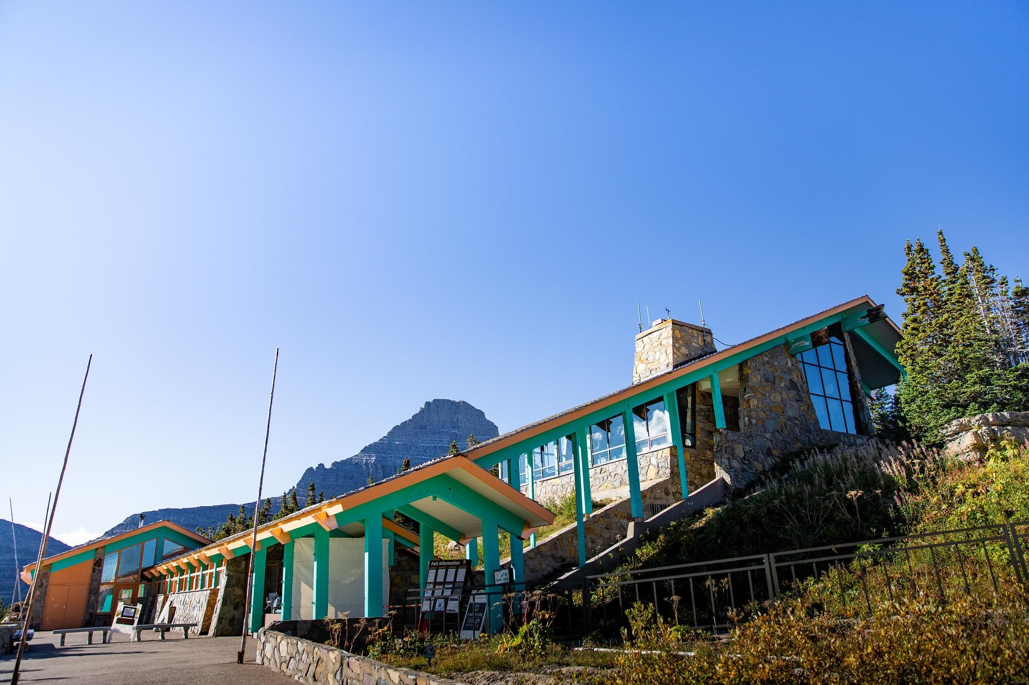 A view of Logan Pass Visitor Center with Mt. Reynolds in the background and vegetation in front.