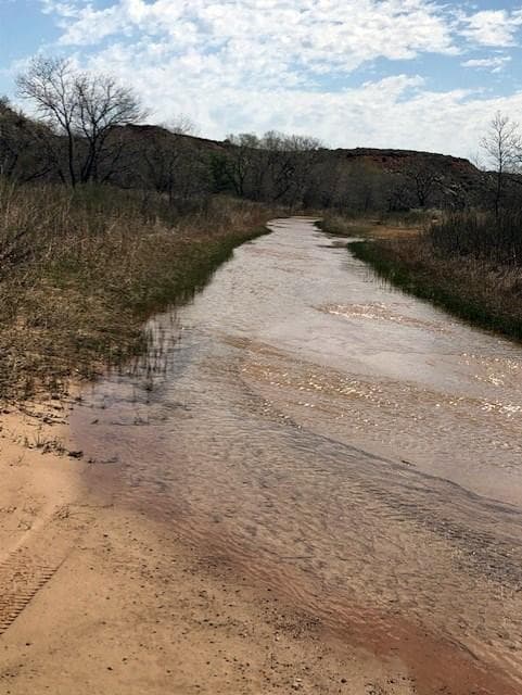 Blue Creek during a wet season. The water is orange colored and the sky is blue.