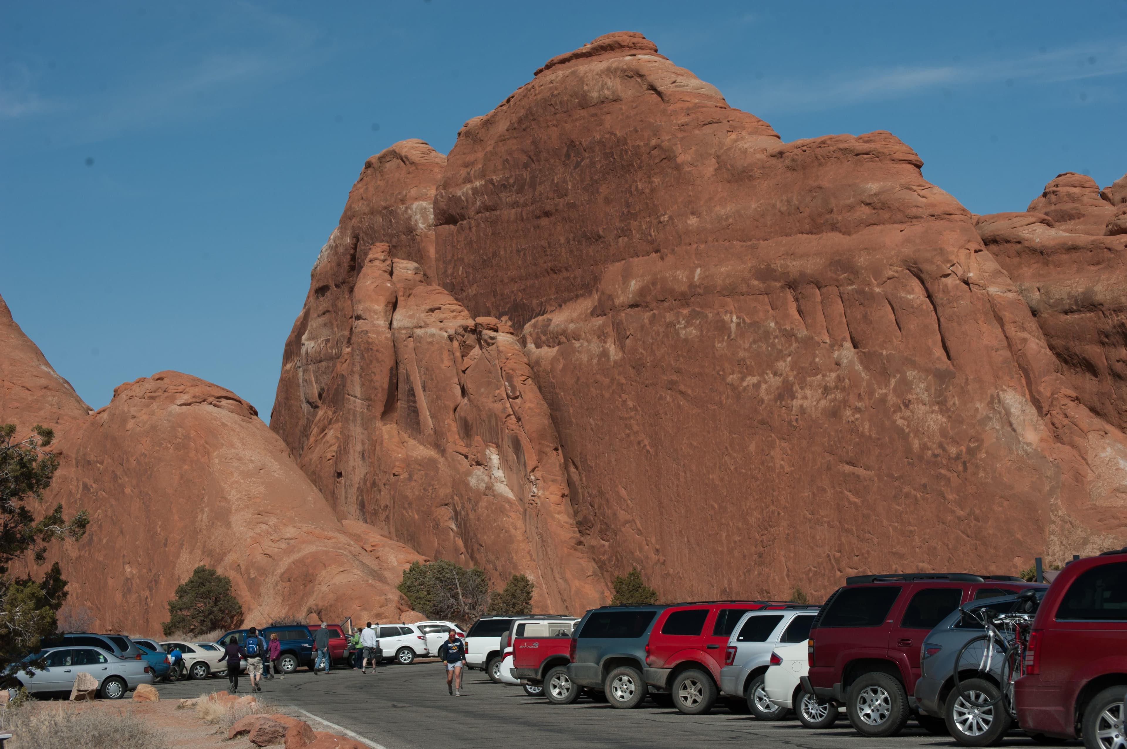several vehicles in a parking lot with rock walls in the background