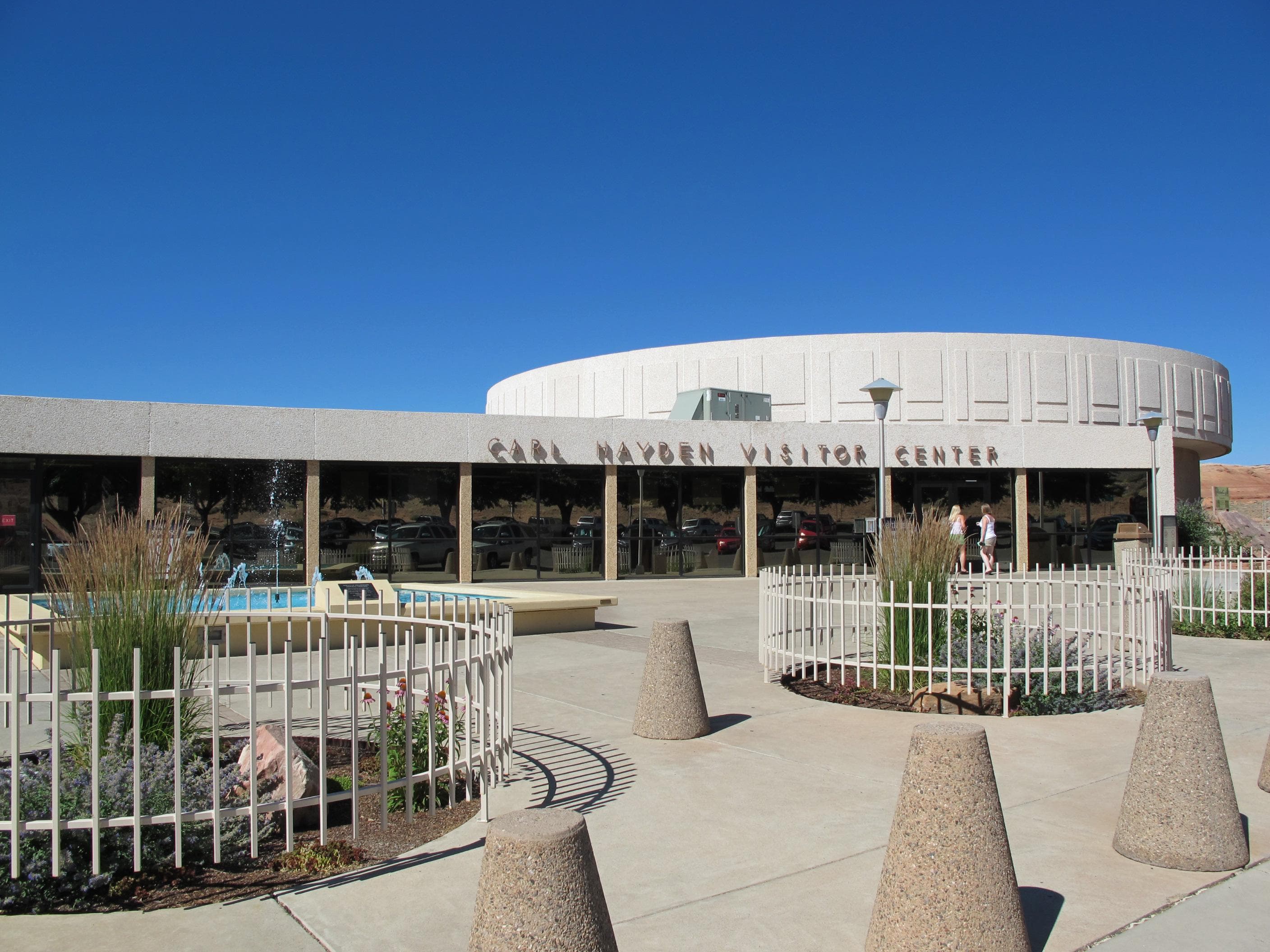 Modern building with concrete barriers in front. Carl Hayden Visitor Center on front of building.