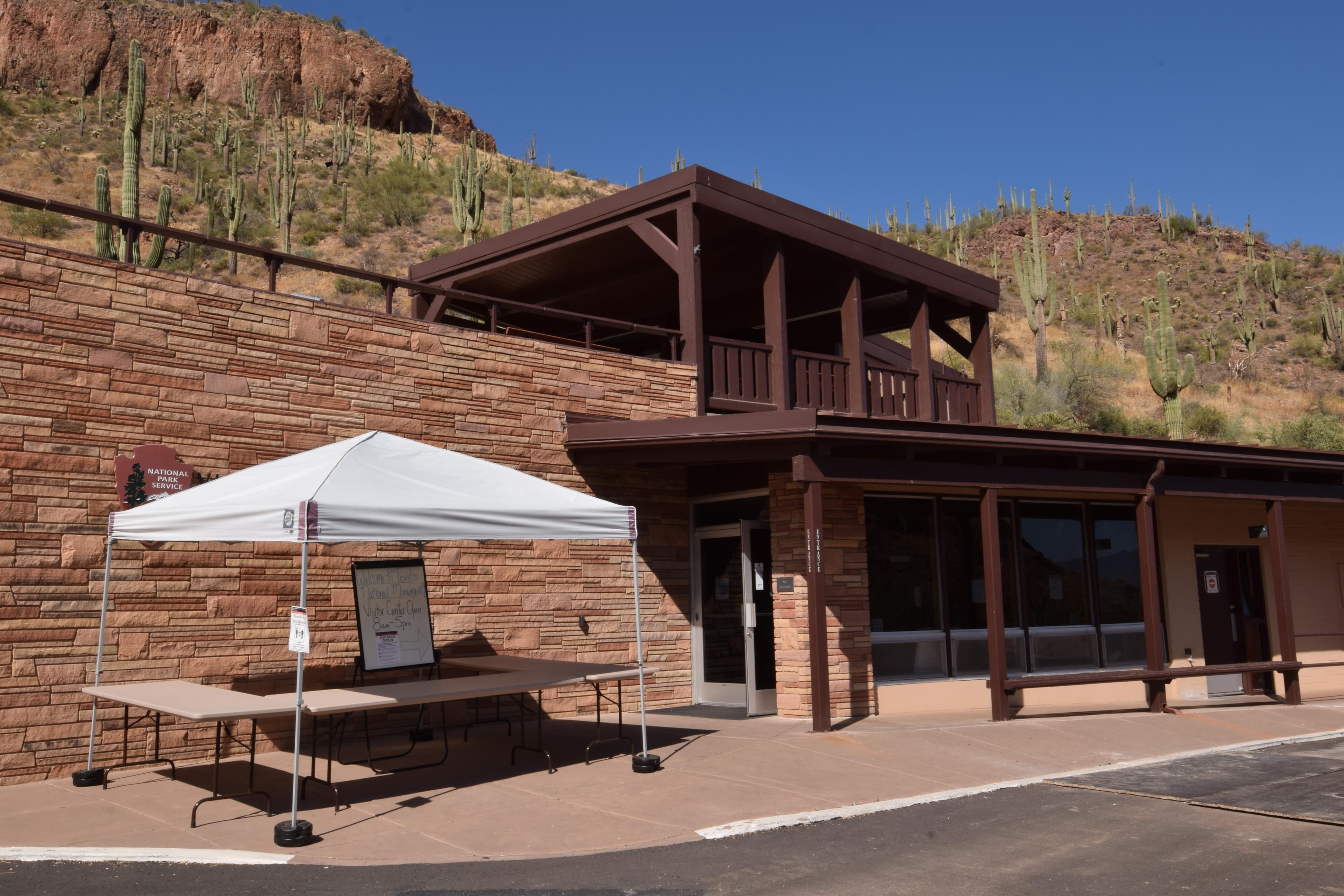 Front entrance of a stone Visitor Center. Single story with an outside viewing platform on top.