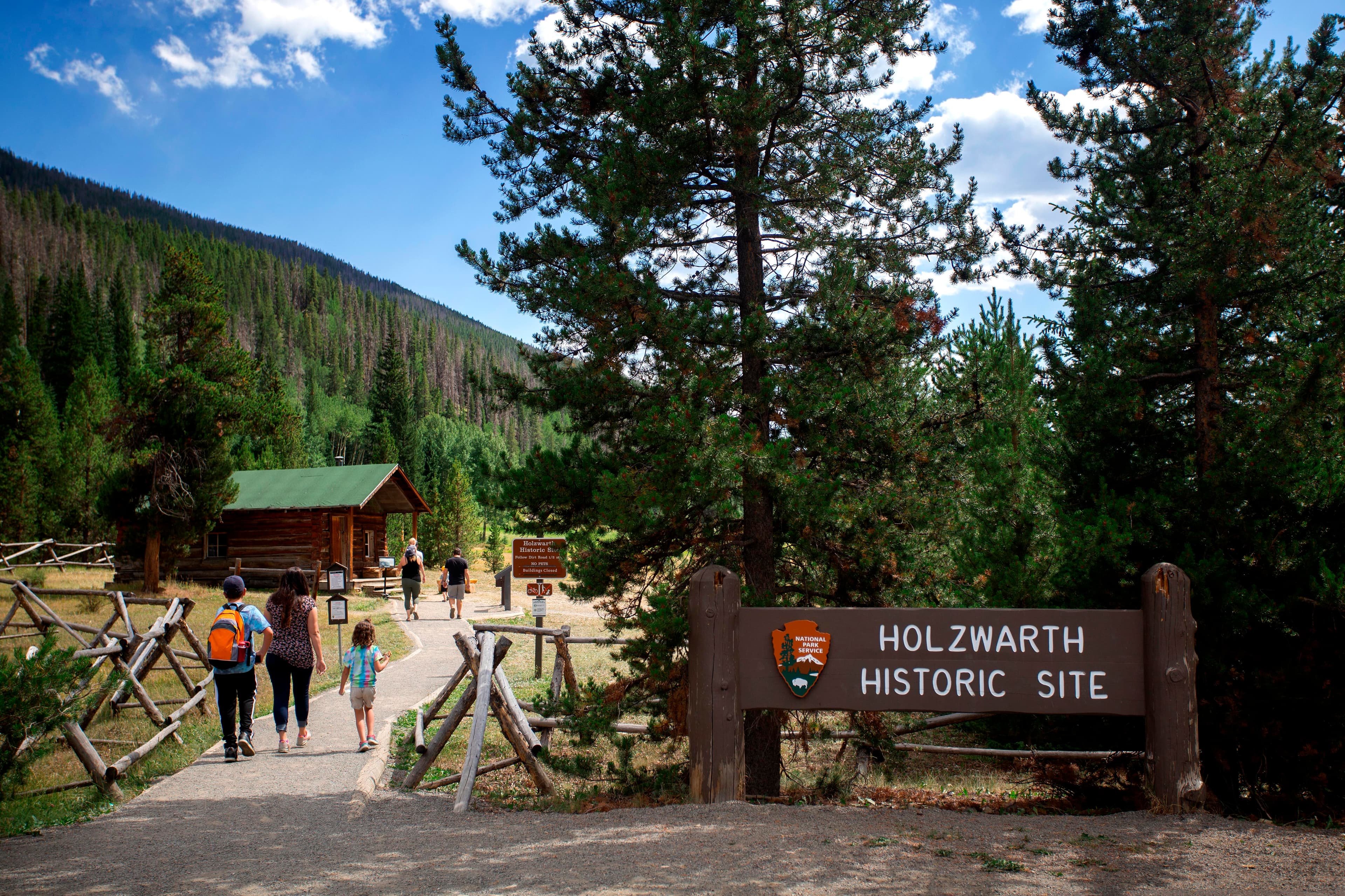 Entrance sign and visitors are walking on the trail to the Holzwarth Historic Site