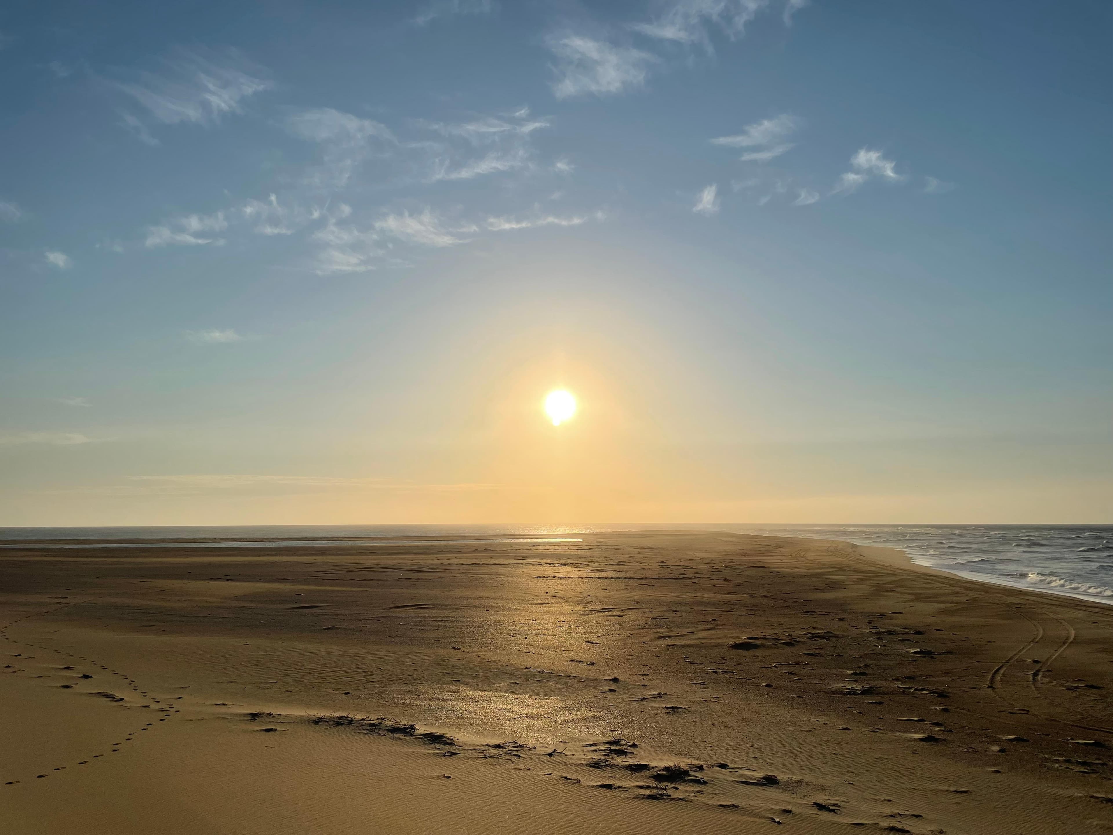 a yellow glow of the risiing sun over the beach and ocean