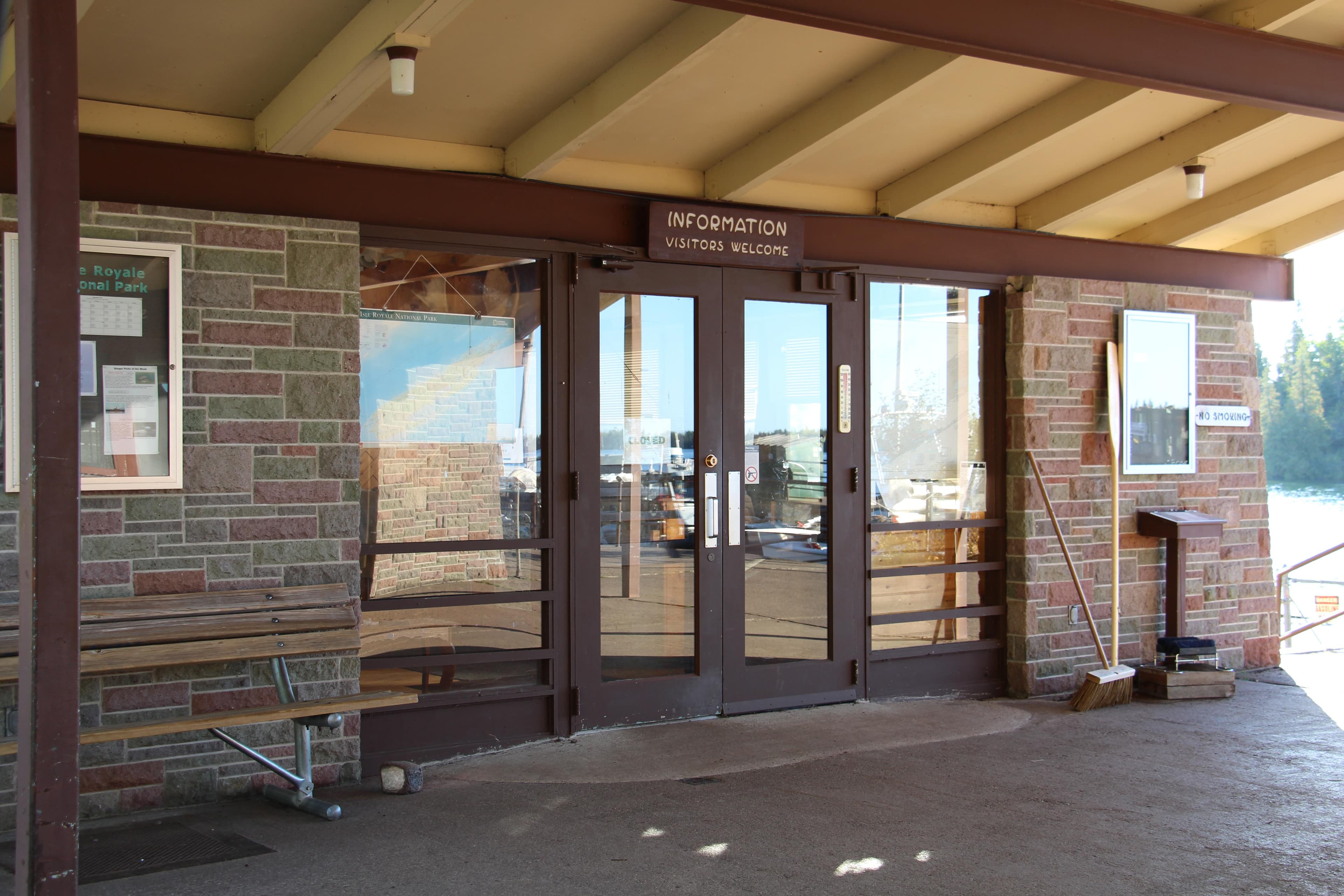 A building with brown paint and brick has double doors with a sign that reads "Information" above it