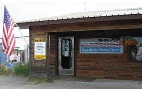 Wood sided structure with sign to right of door saying: King Salmon Visitor Center
