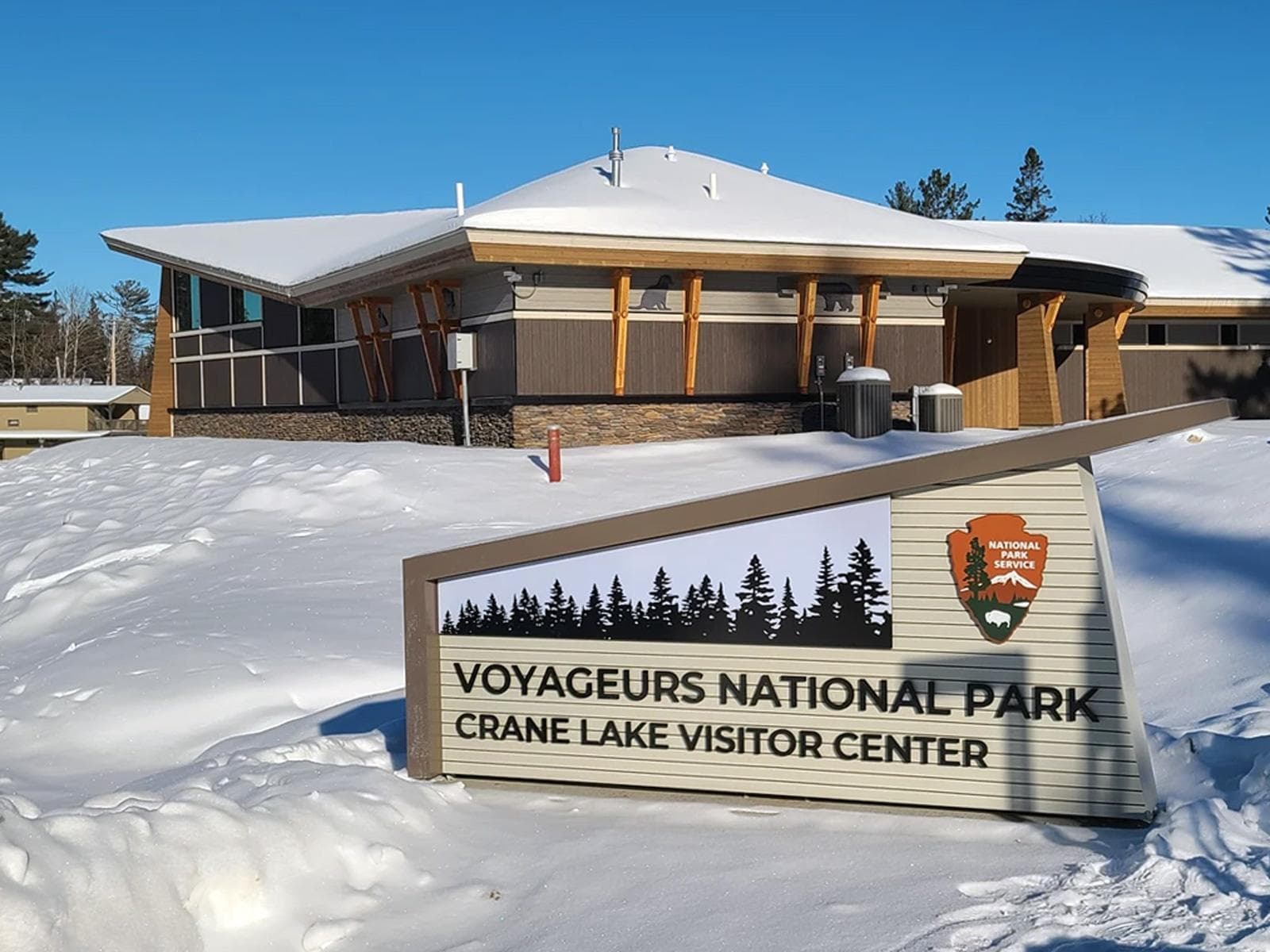 Photograph of National Park Service sign with "Crane Lake Visitor Center" in black lettering.
