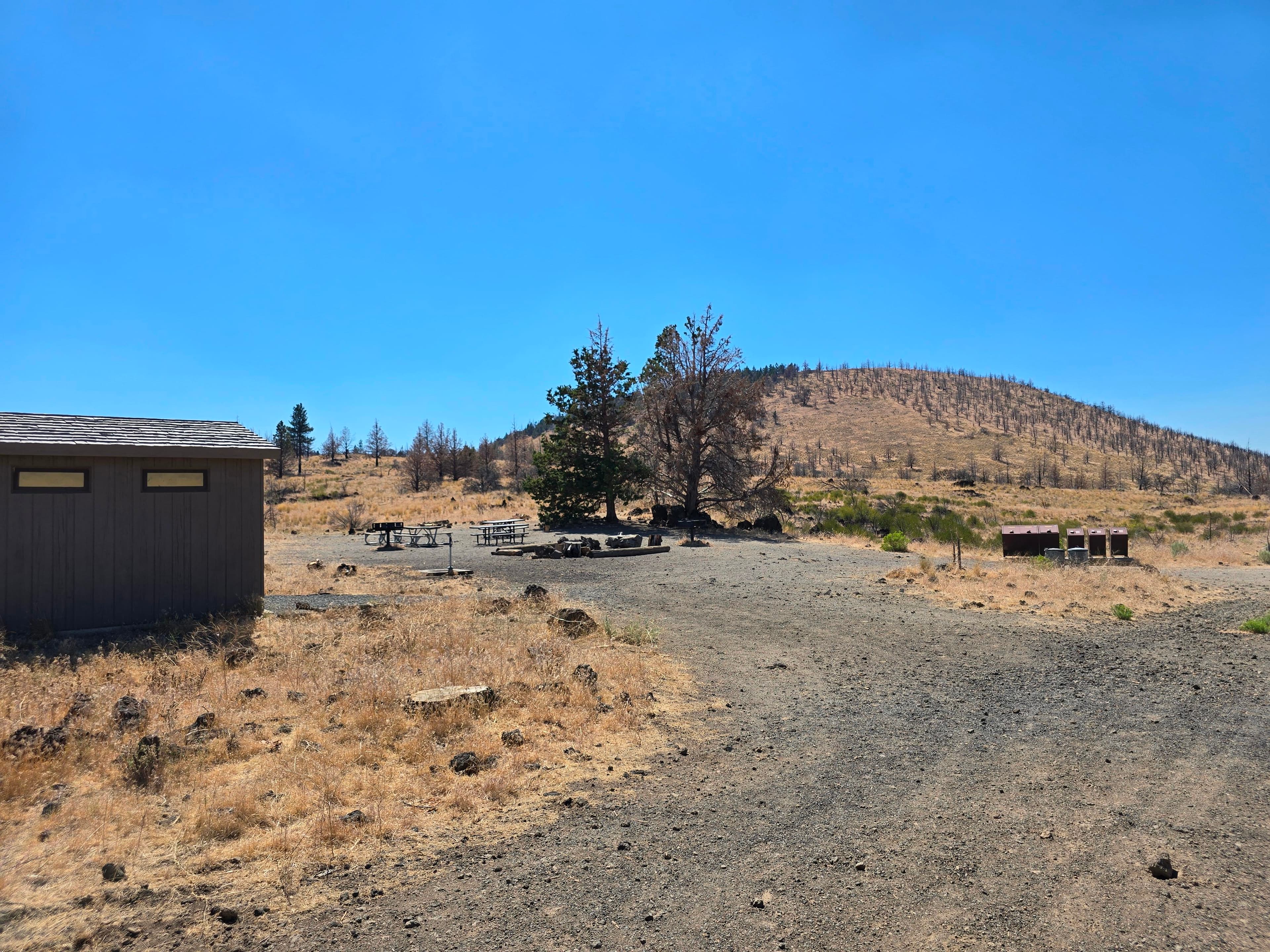 Looking towards group site, brown bathroom building on the left, and picnic tables in the background