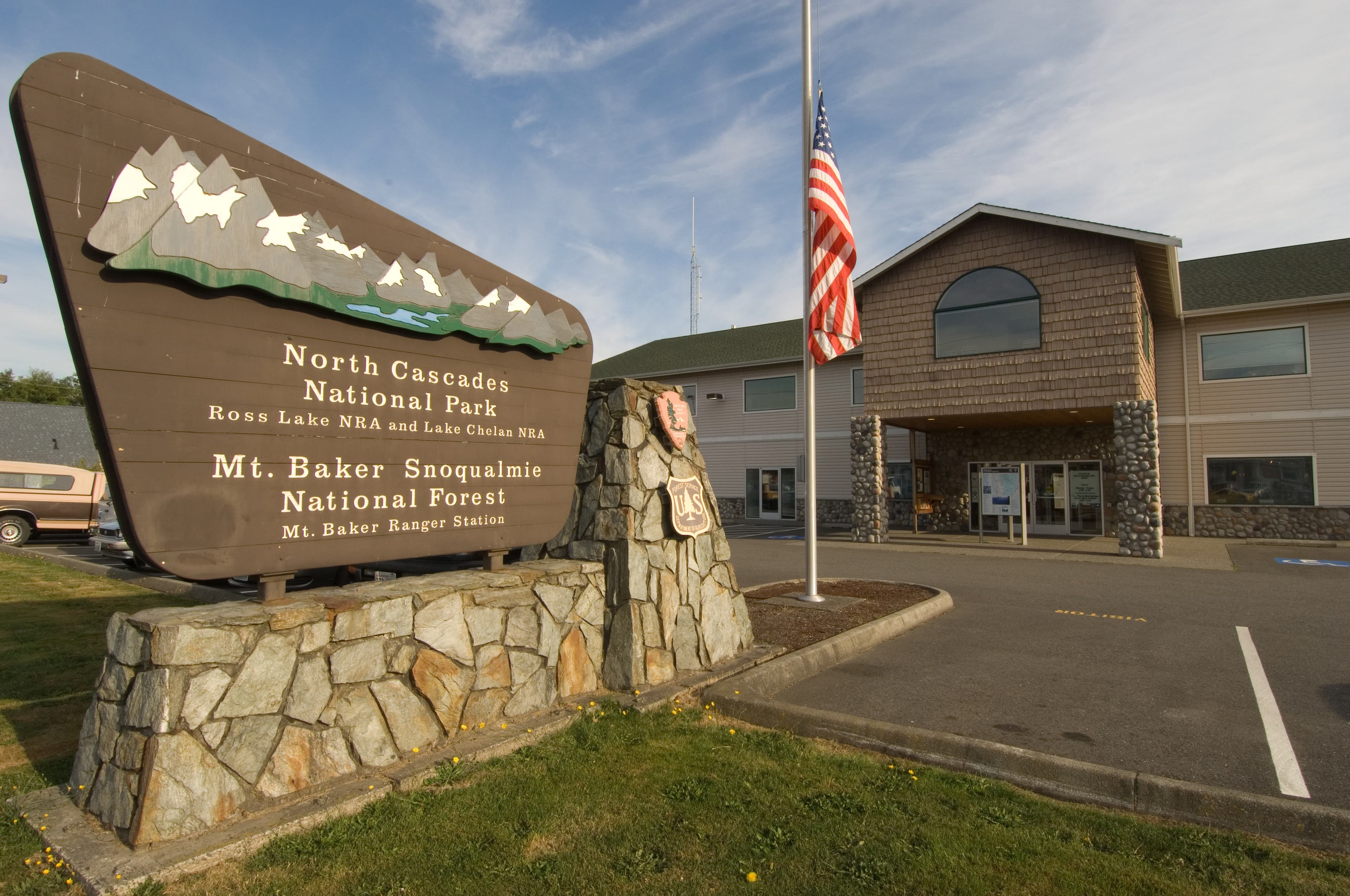 A stone and wood sign in front of a brown building.