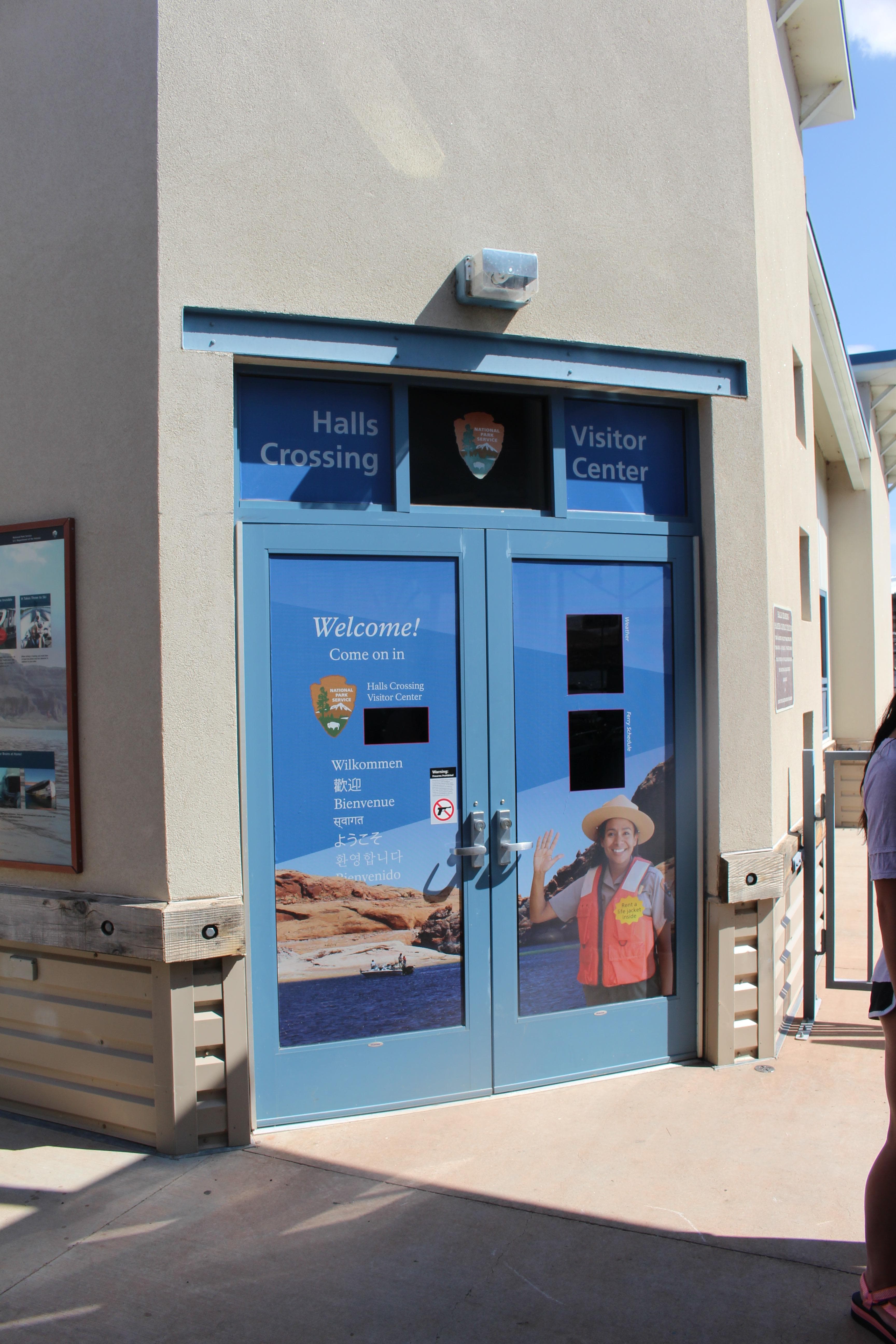 Two doors on a thin building decorated with a waving park ranger