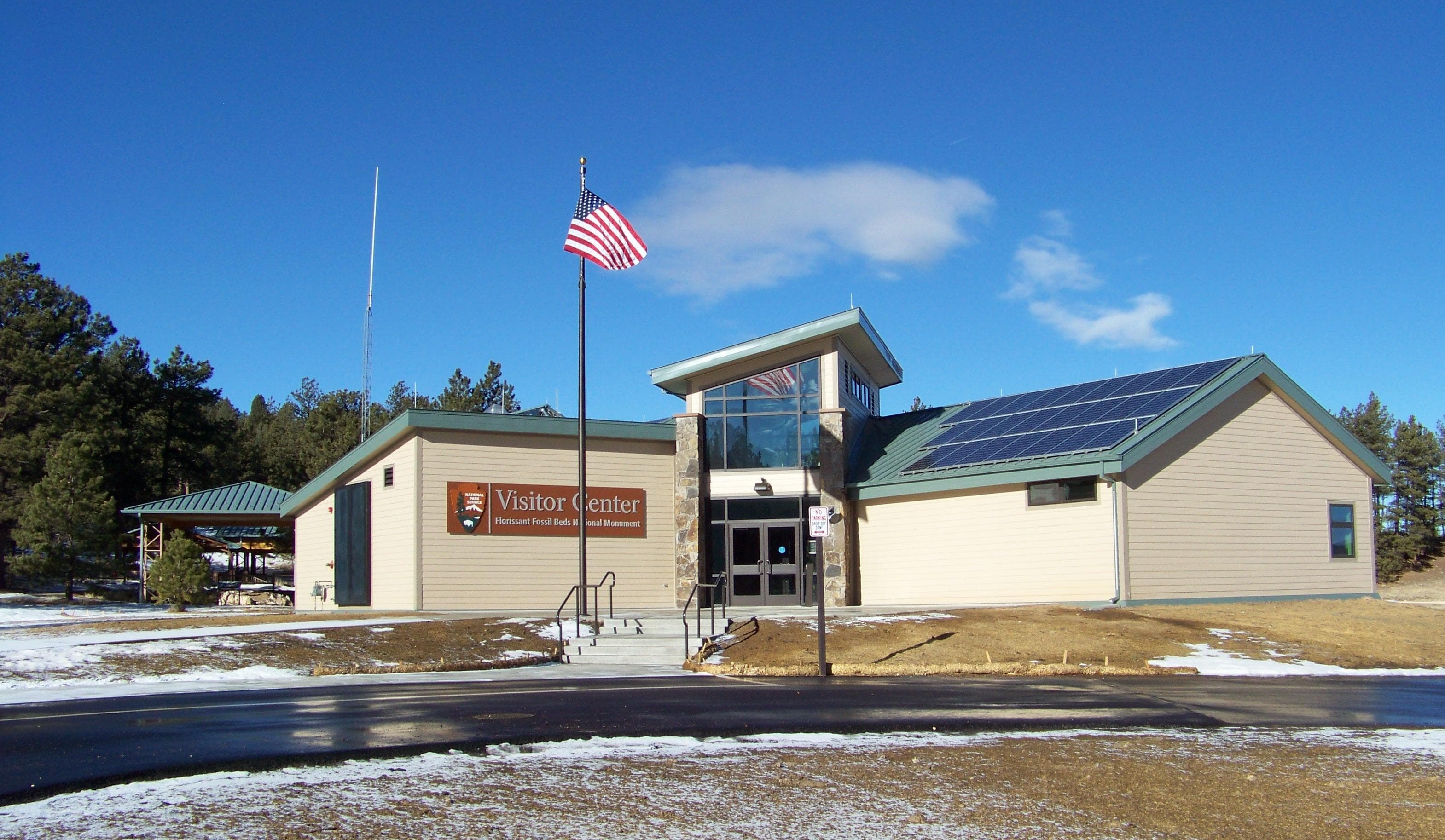 Florissant Fossil Beds Visitor Center with blue sky behind, flag waiving in wind in front