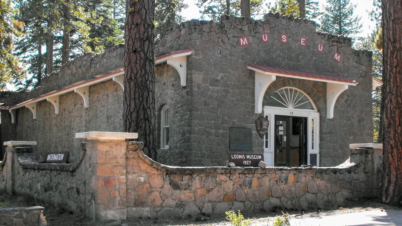 A one-story stone building surrounded by a short stone wall.