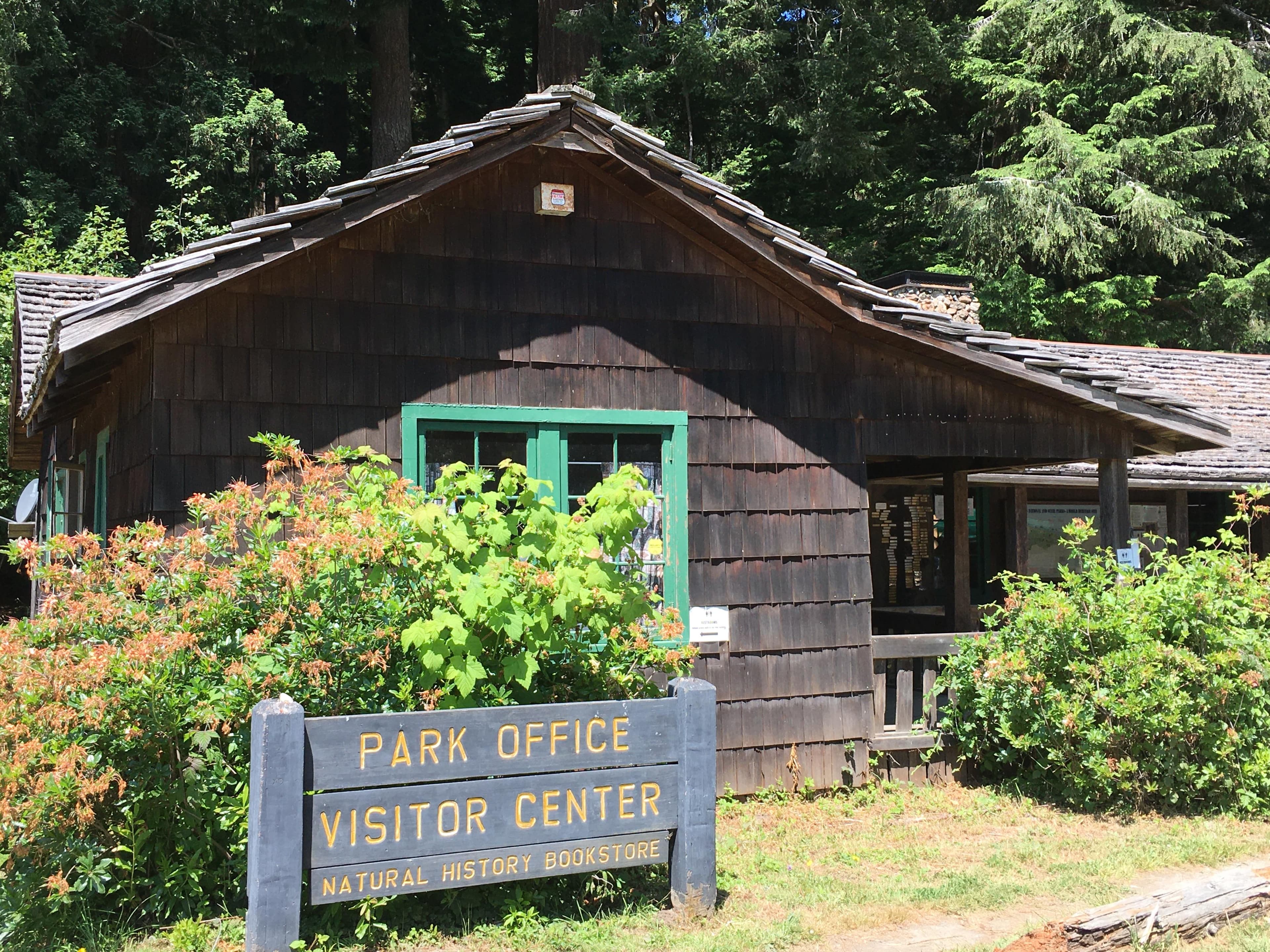 A wooden building next to redwood trees.