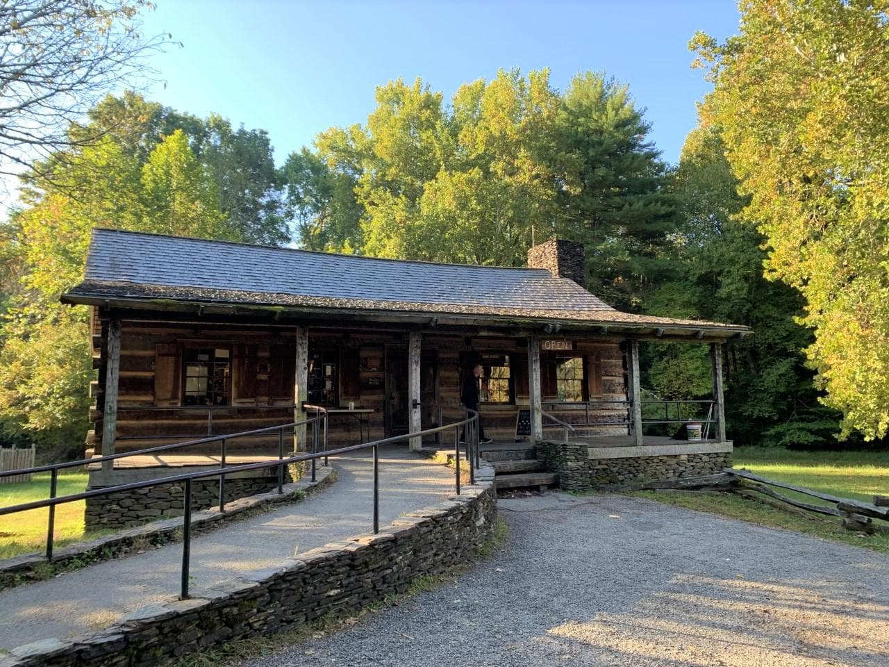 A park visitor center built like a log cabin with a covered porch, chimney, and paved approach ramp.
