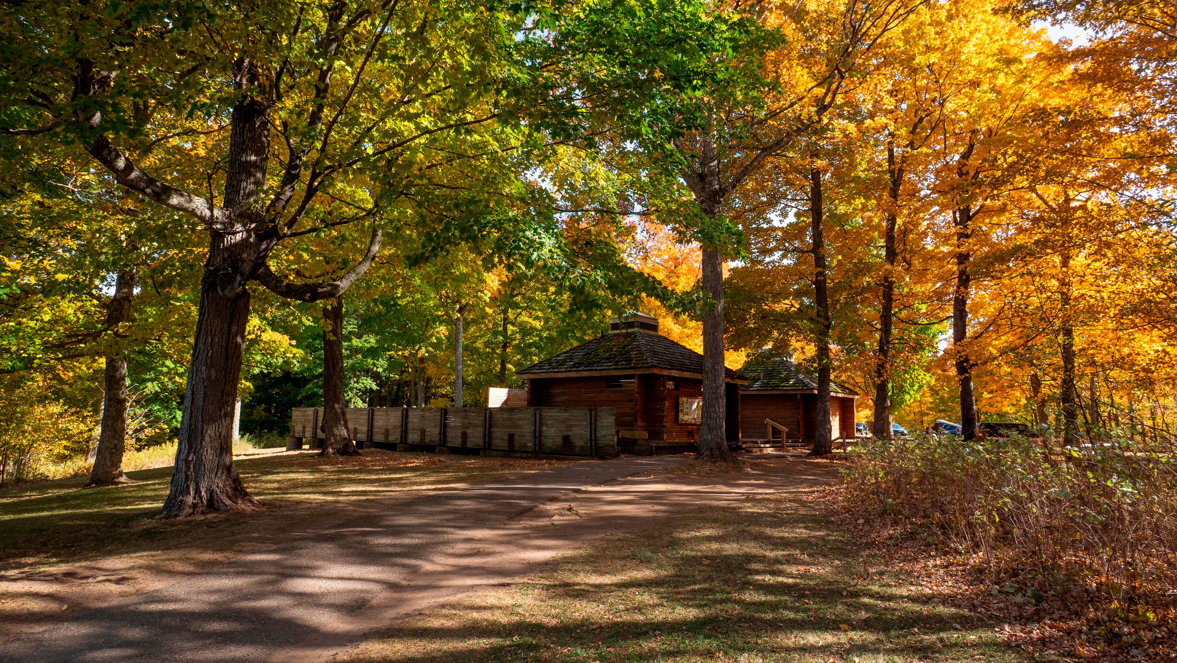 A wood pavilion beneath autumn trees.
