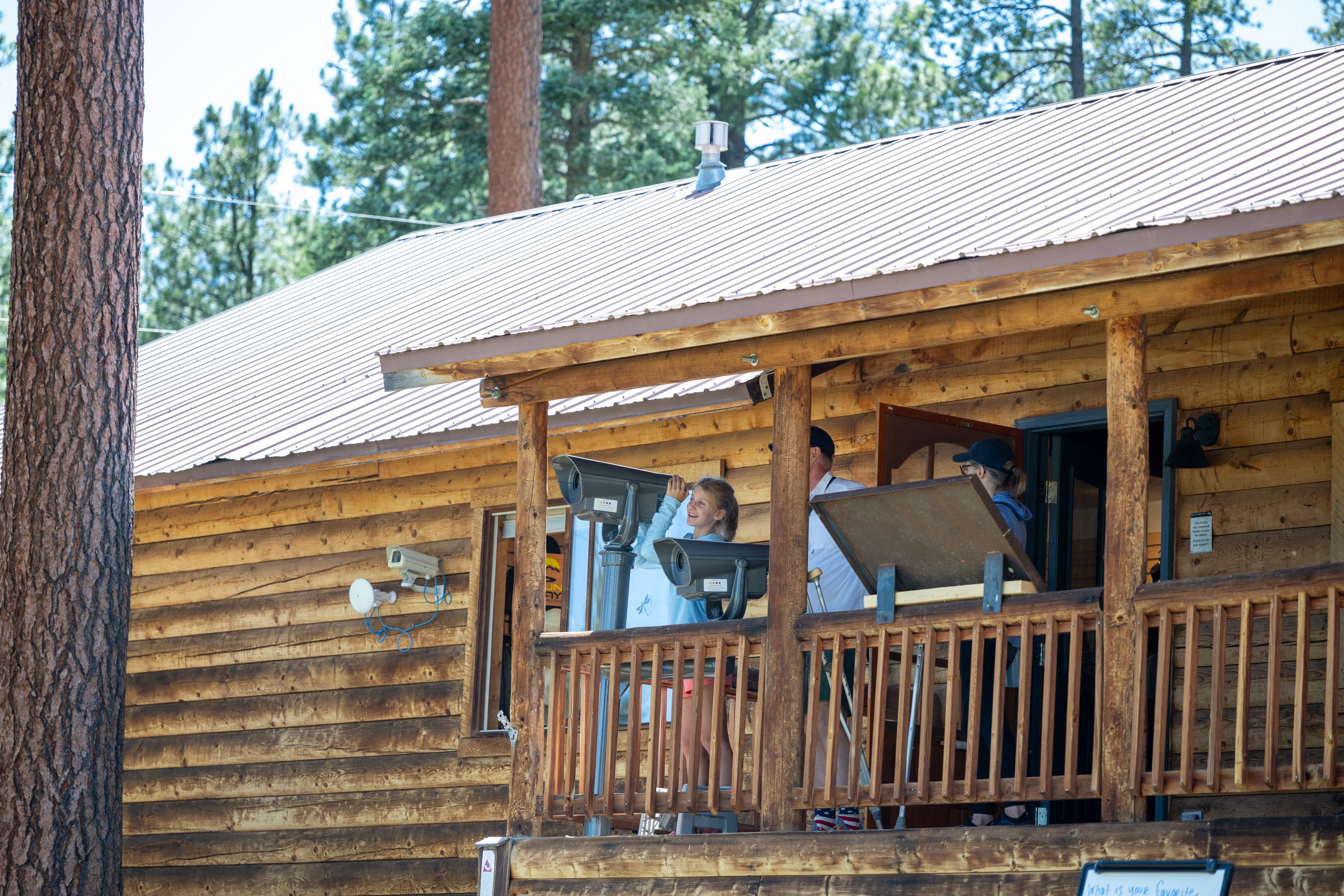People standing on the front porch of a log cabin.