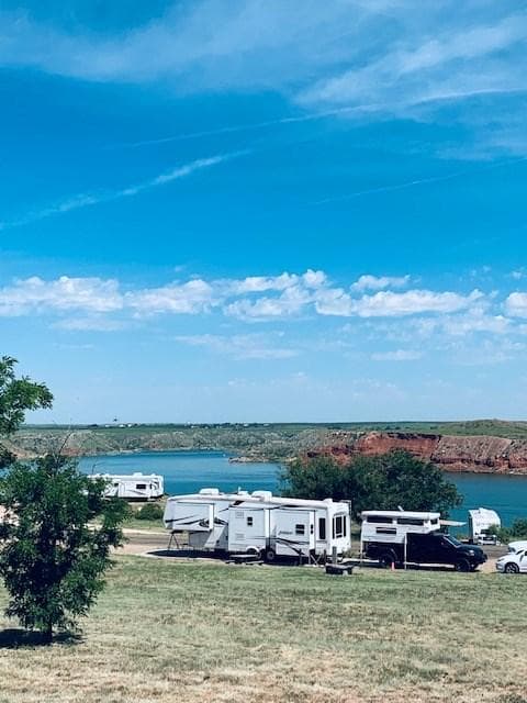 Sanford-Yake Campground with campers along the edge. The sky is blue with white clouds.