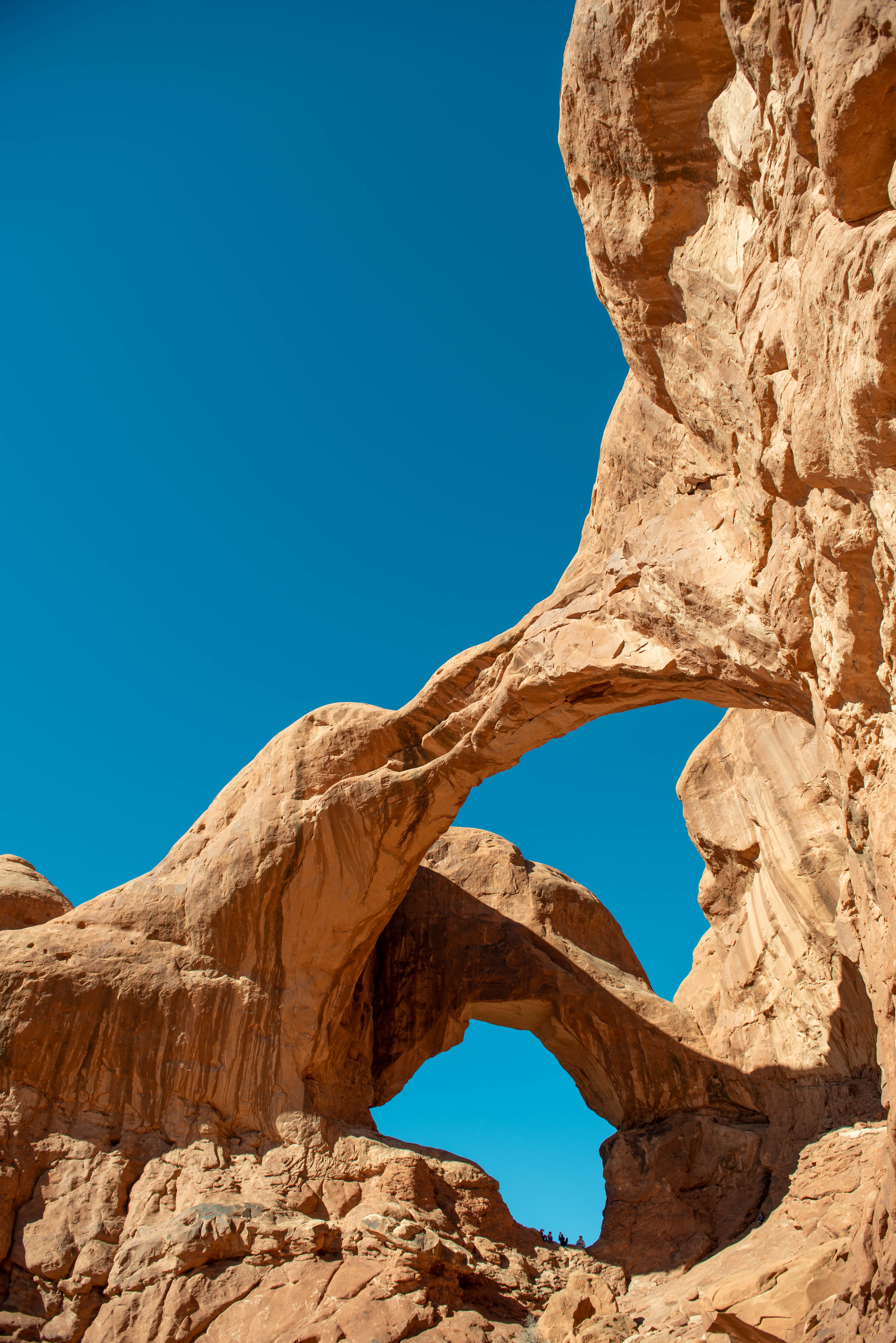 Two sandstone arches reach across a blue sky.