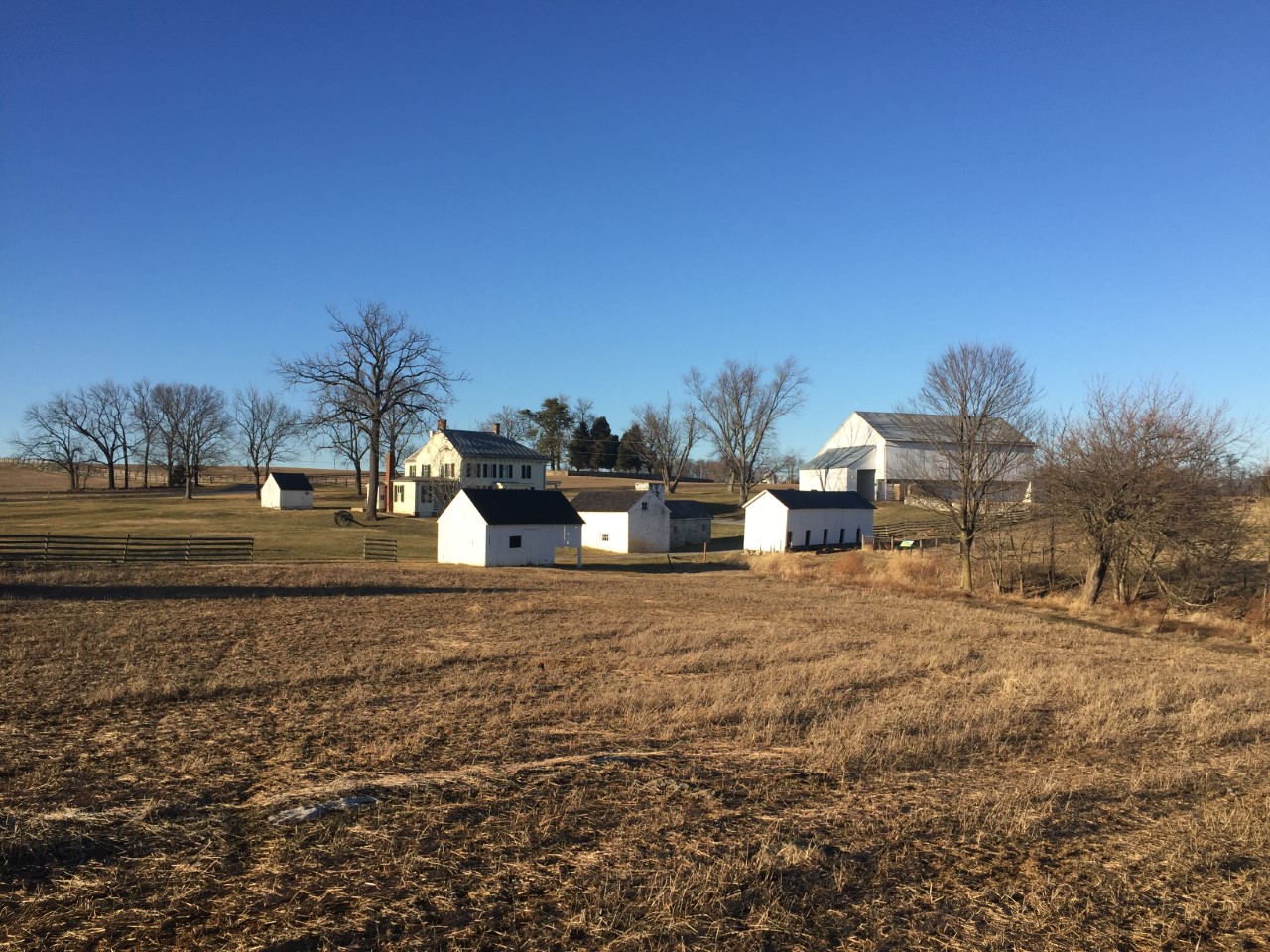 numerous buildings, including a house and barn set off in a field