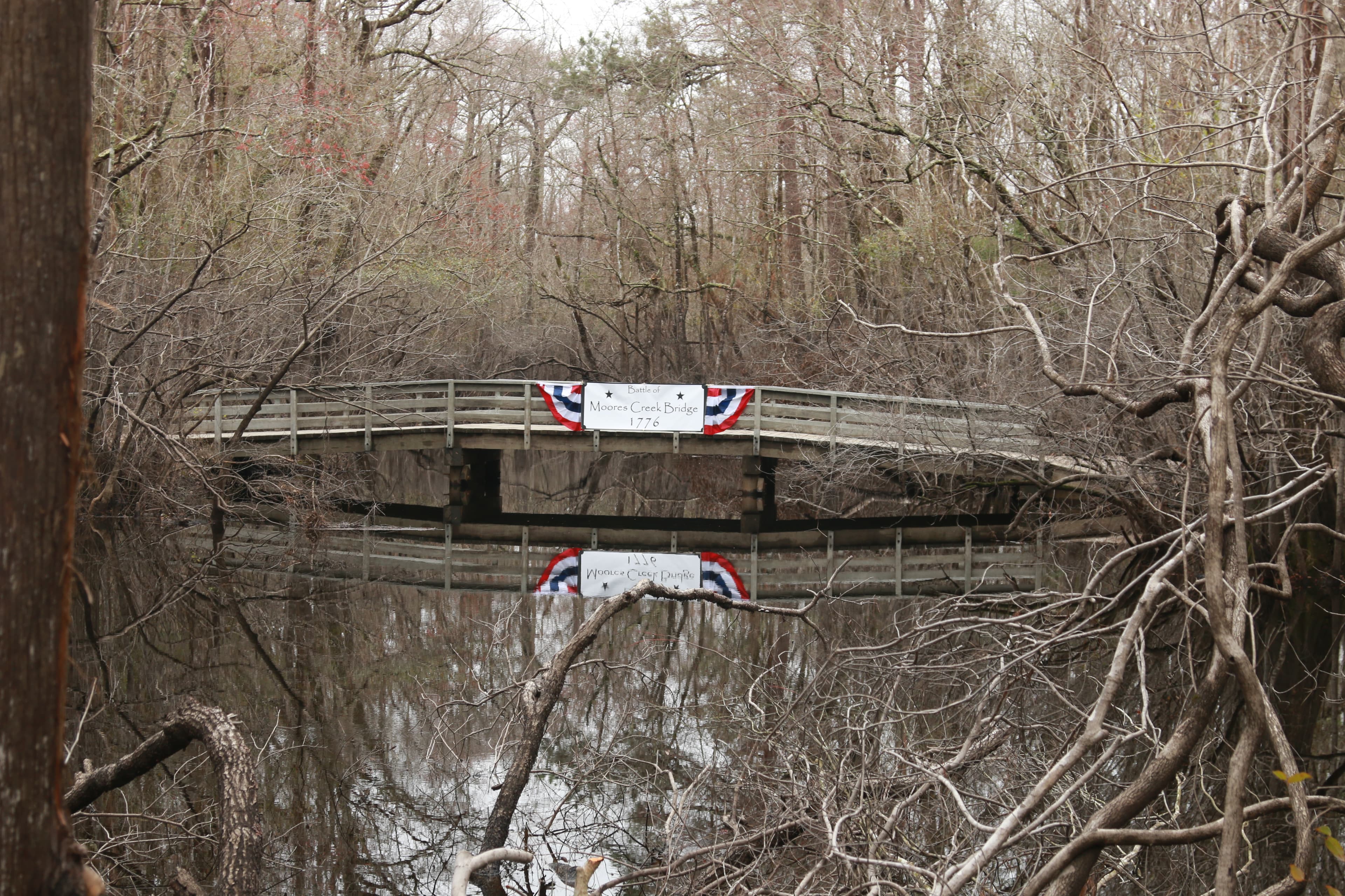 Bridge over a creek with a patriotic banner hanging on it.