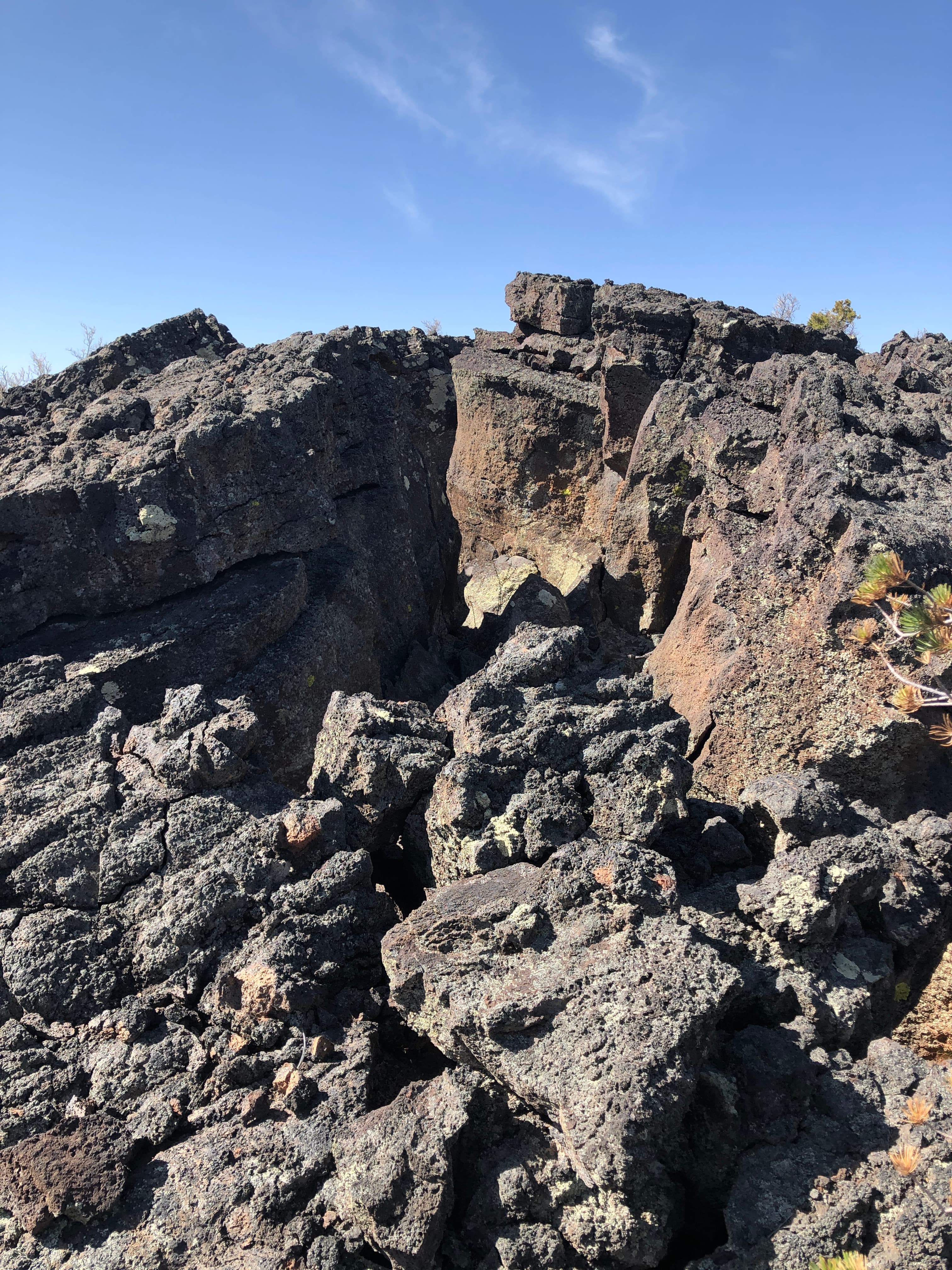 A wide and jagged crack splits two thick slabs of black lava rock directly down the middle.