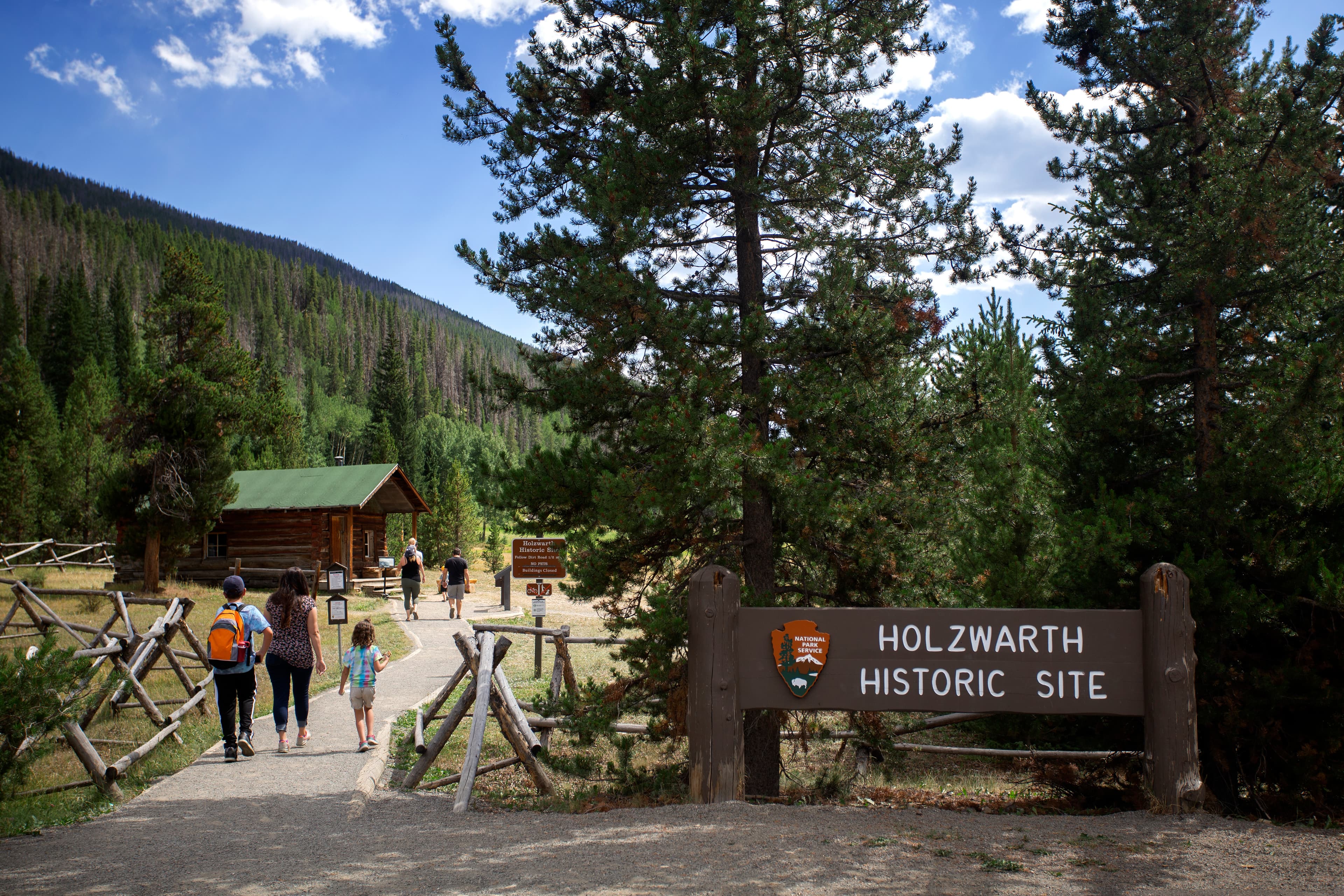 Visitors are walking on the dirt path, entering the Holzwarth Historic Site