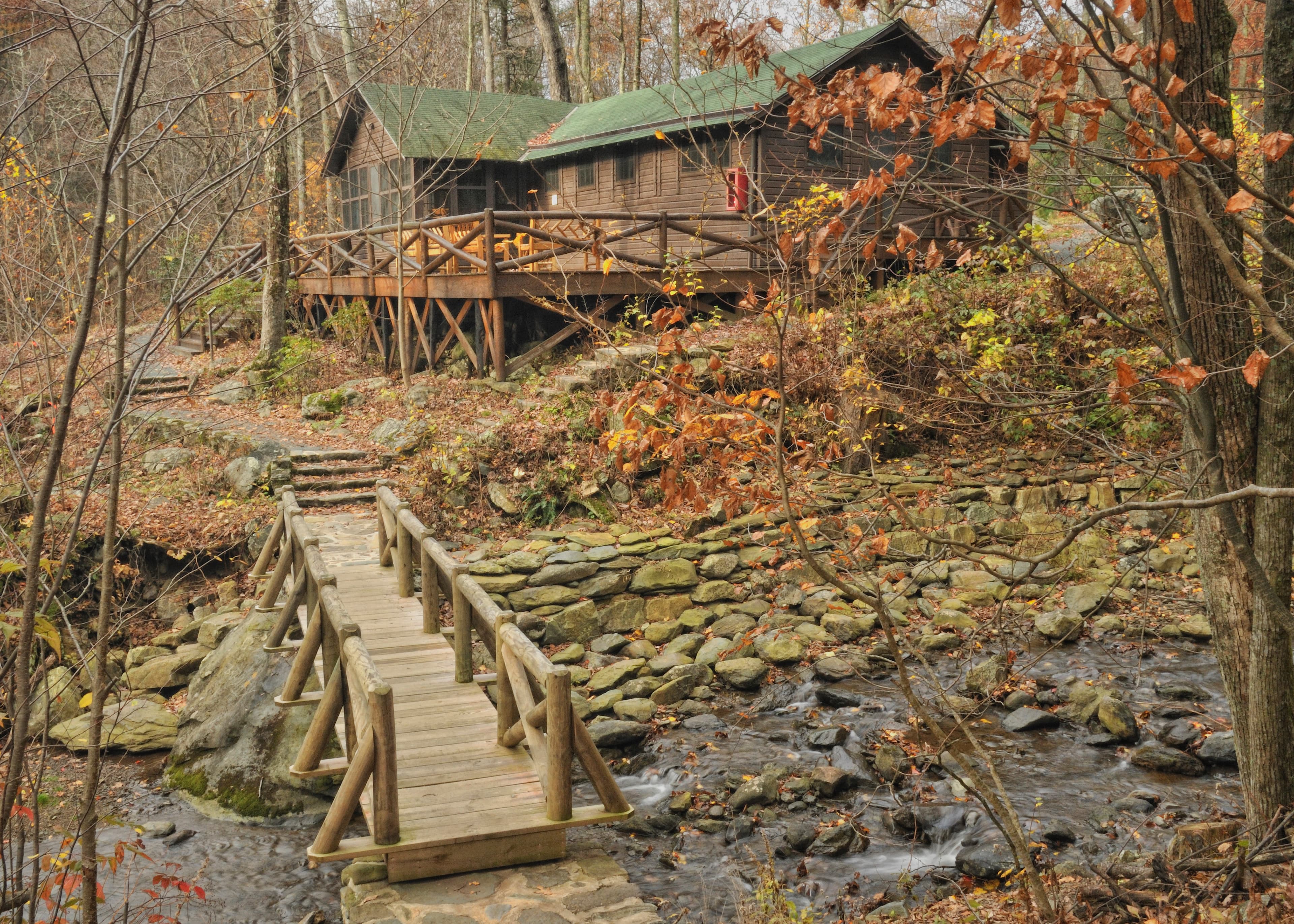 A fall scene with a creek and rustic bridge in the foreground and the