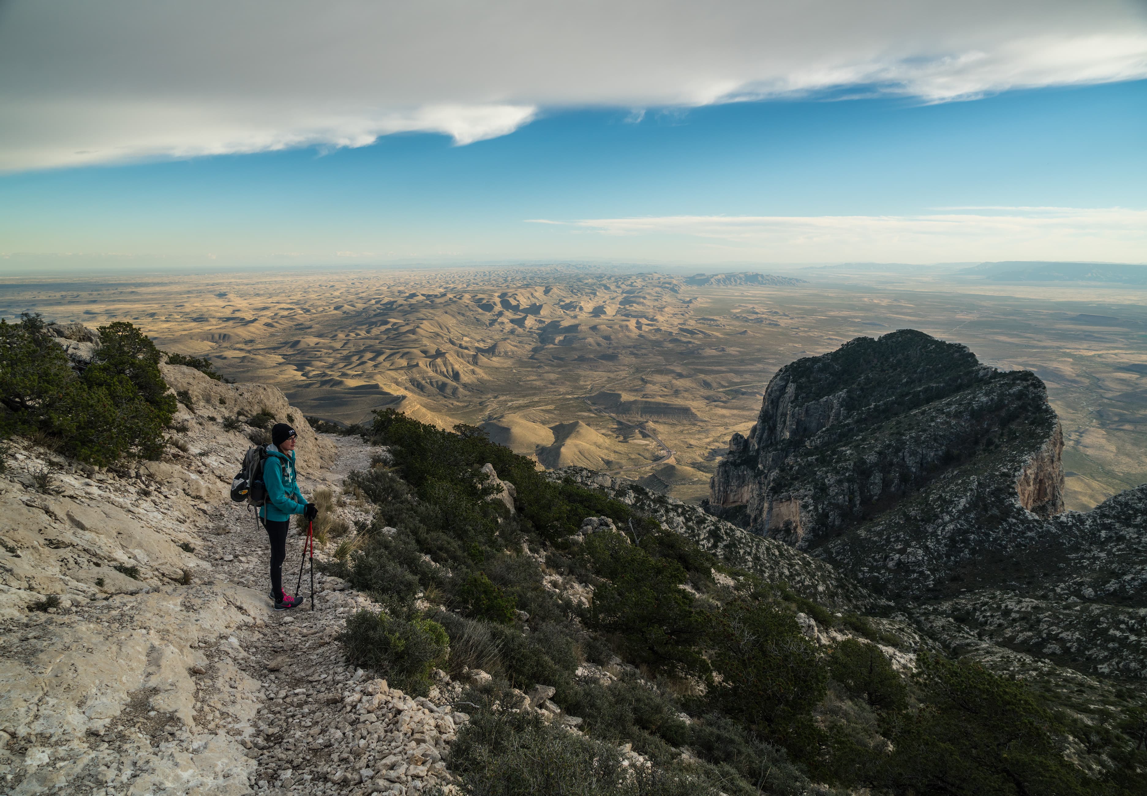 A hiker stands on the trail to Guadalupe Peak to the right the summit of El Capitan can be seen