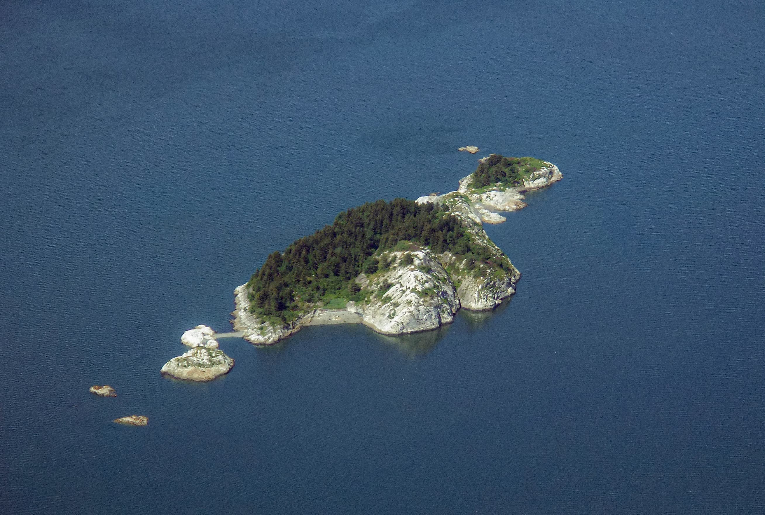 aerial view of south marble island, a rocky outcropping. Trees and green cover the higher parts.